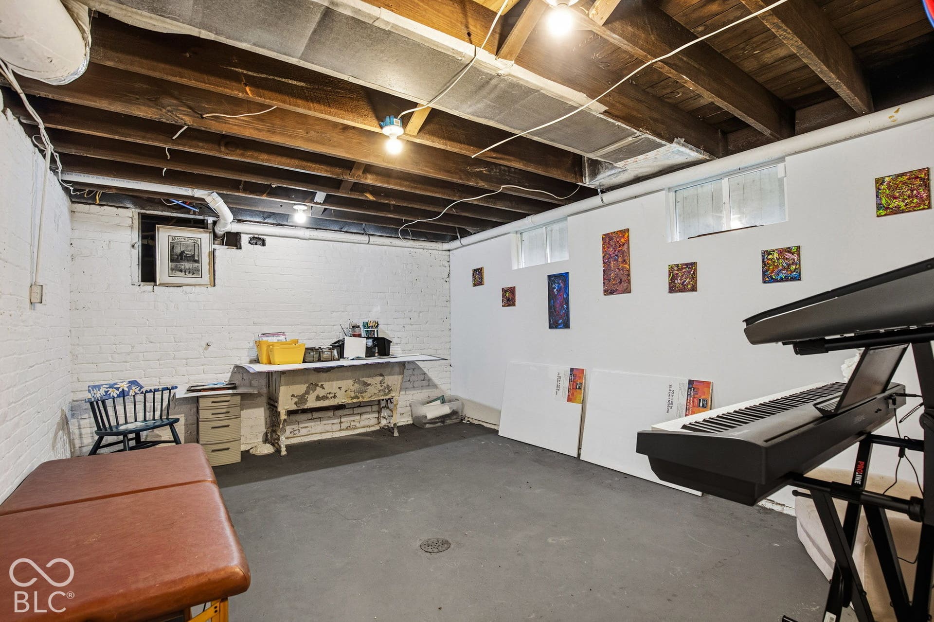 Unfinished space with exposed wood joist ceilings, painted brick walls, and concrete flooring featuring multiple windows for natural light