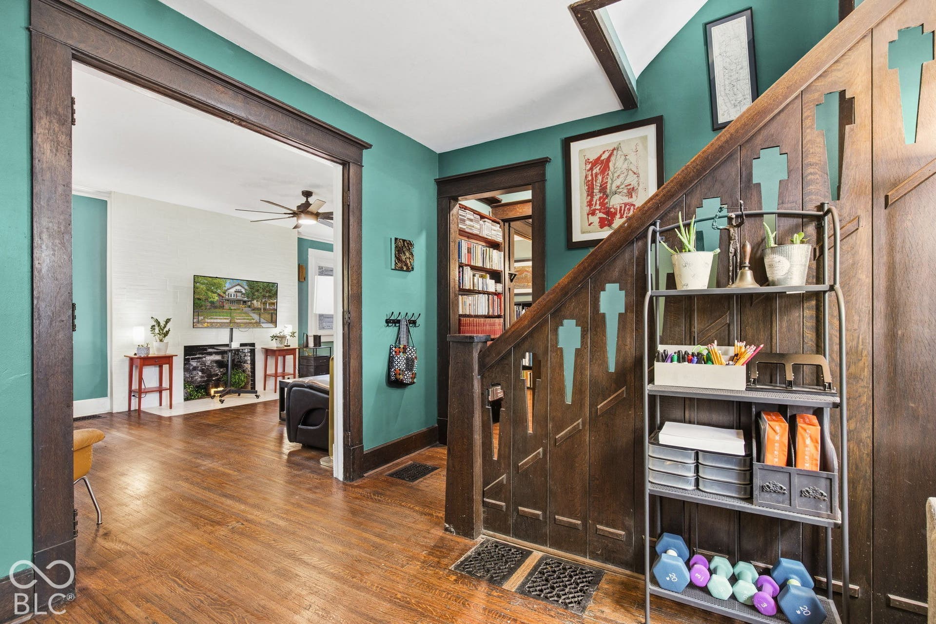 Staircase featuring dark-stained wood paneling with decorative cutouts, original millwork trim, and wood-finish flooring