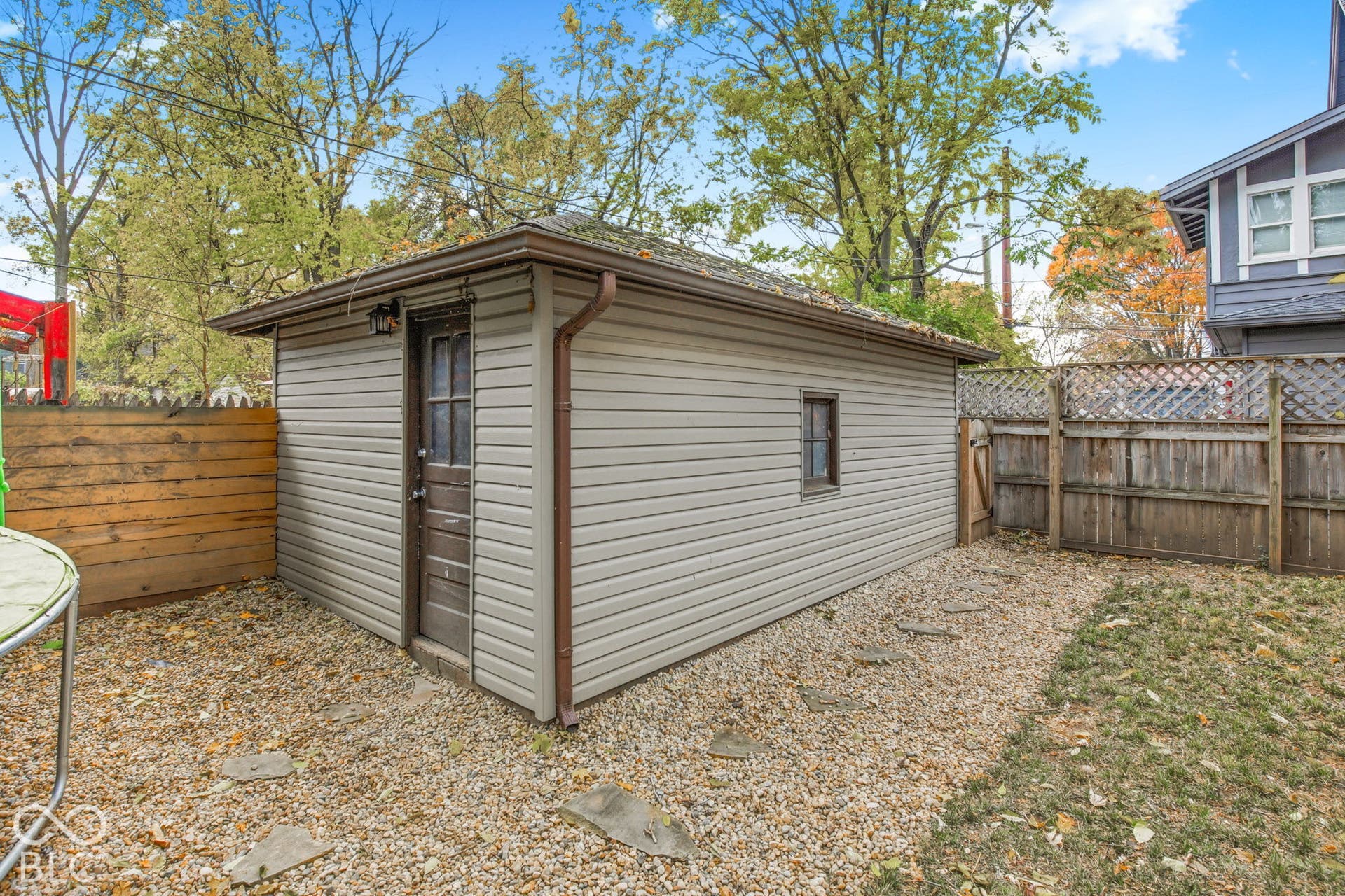 Detached outbuilding featuring horizontal siding, a hipped roof, a single-door entry with window panes, and an integrated gutter system