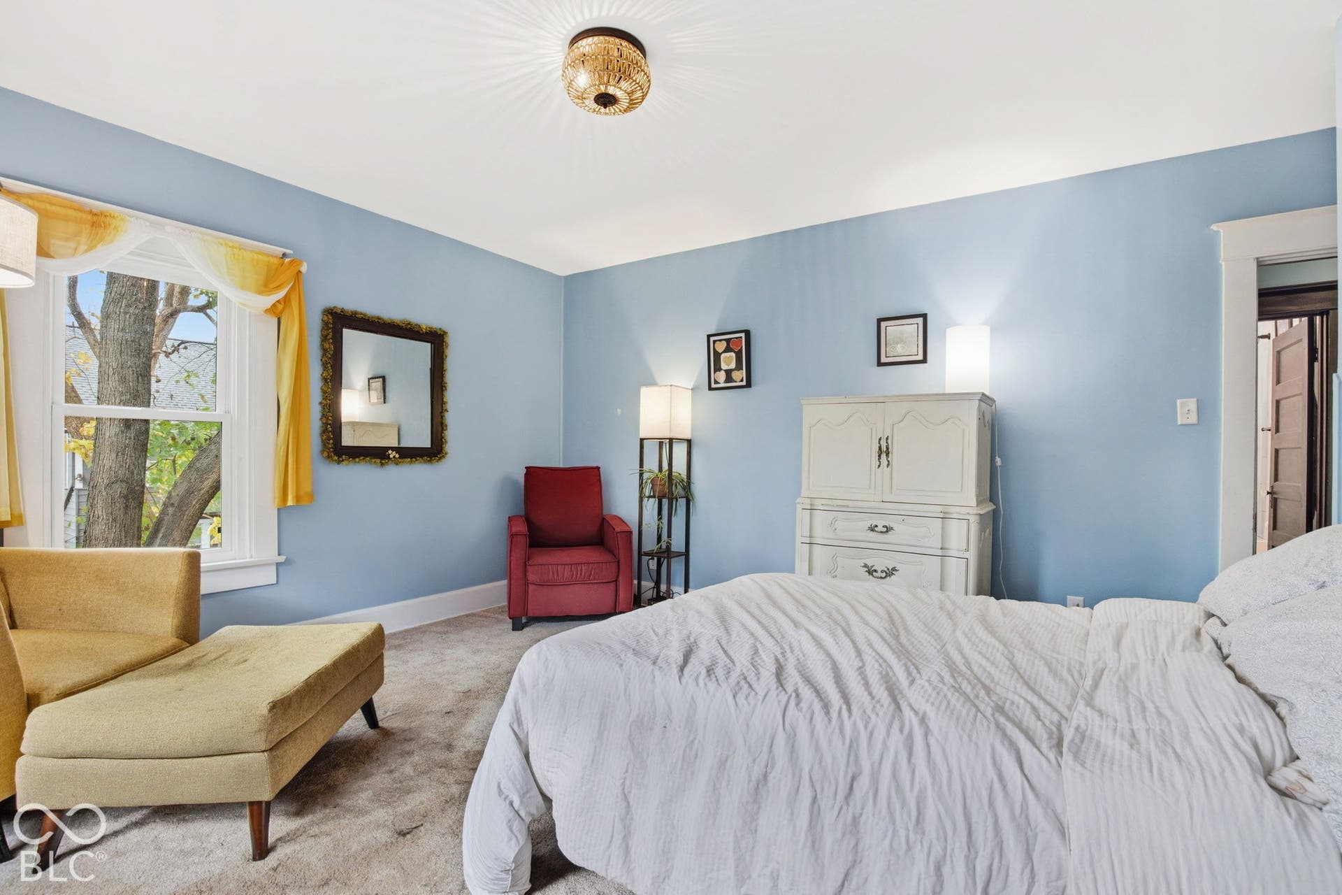 Neutral-toned carpeting, window featuring thick casing, and central flush-mount decorative ceiling light fixture