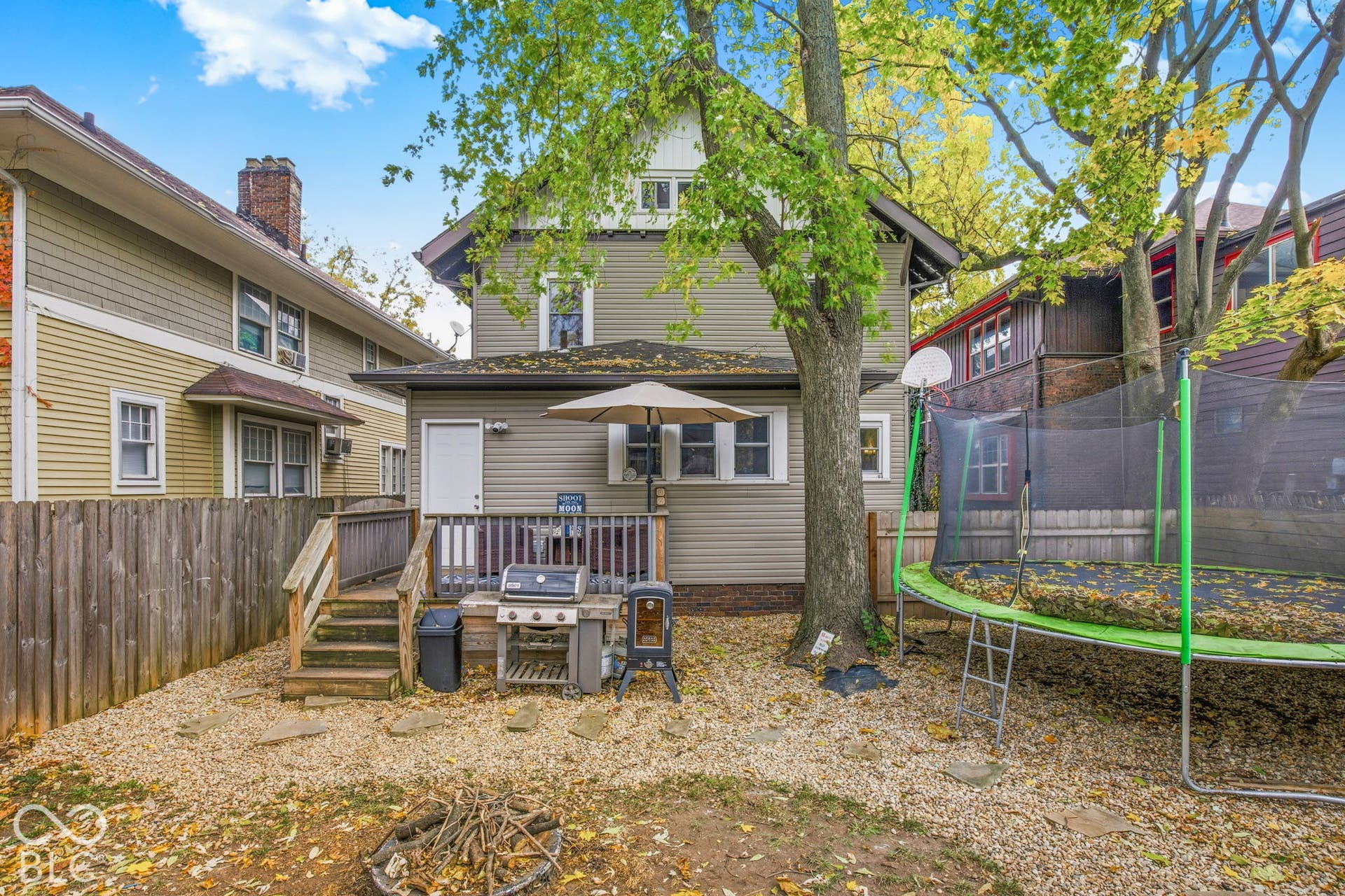 Rear exterior featuring wood siding, an elevated wood deck, and a fenced-in gravel yard