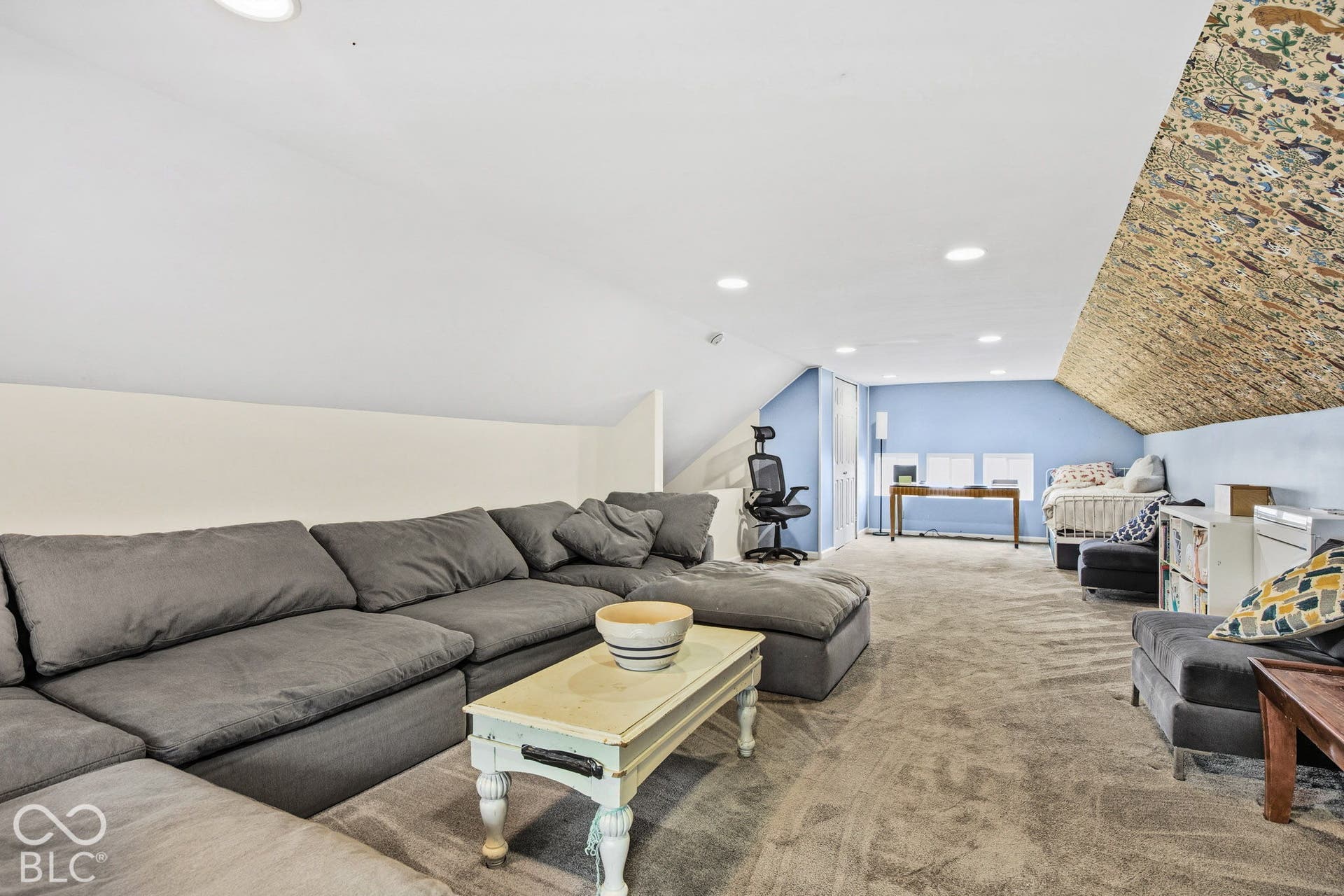 Finished attic featuring neutral carpeting, recessed lighting, and a patterned accent wall following the slope of the ceiling