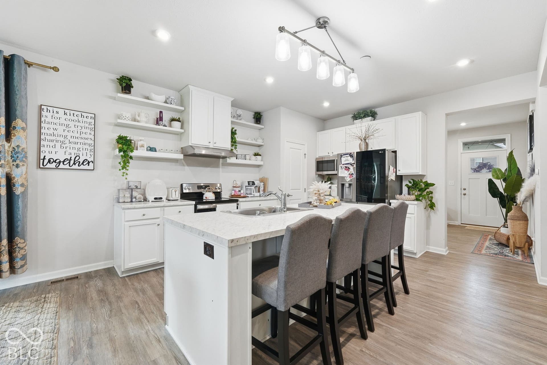 275 Bohicket Road, Whiteland, IN 46184 Kitchen featuring white cabinetry, quartz countertops, a central island with integrated sink, wood-finish flooring, and floating shelving