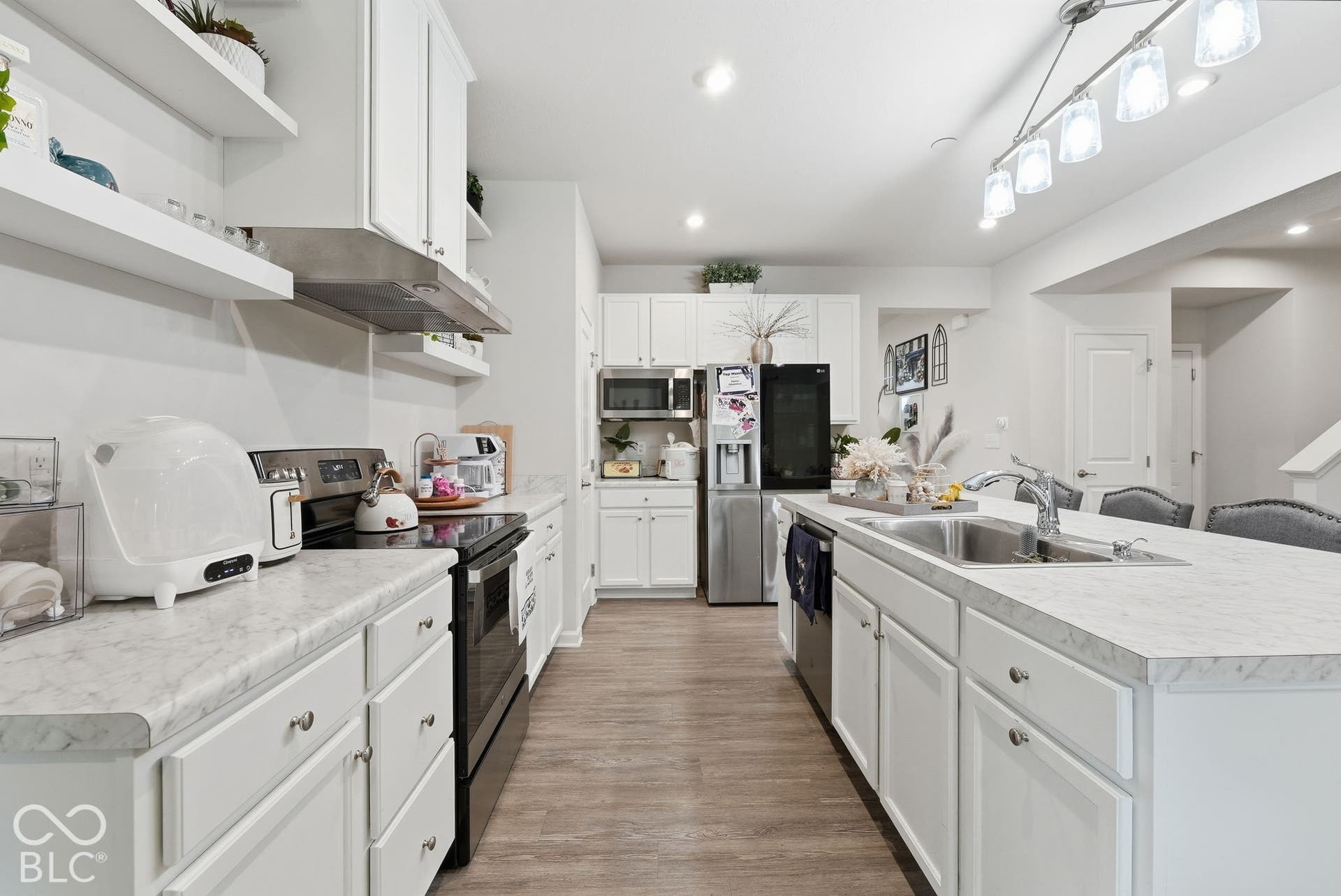 275 Bohicket Road, Whiteland, IN 46184 Kitchen featuring white cabinetry, stone-finish countertops, stainless steel appliances, a center island with a dual-basin sink, and wood-finish flooring