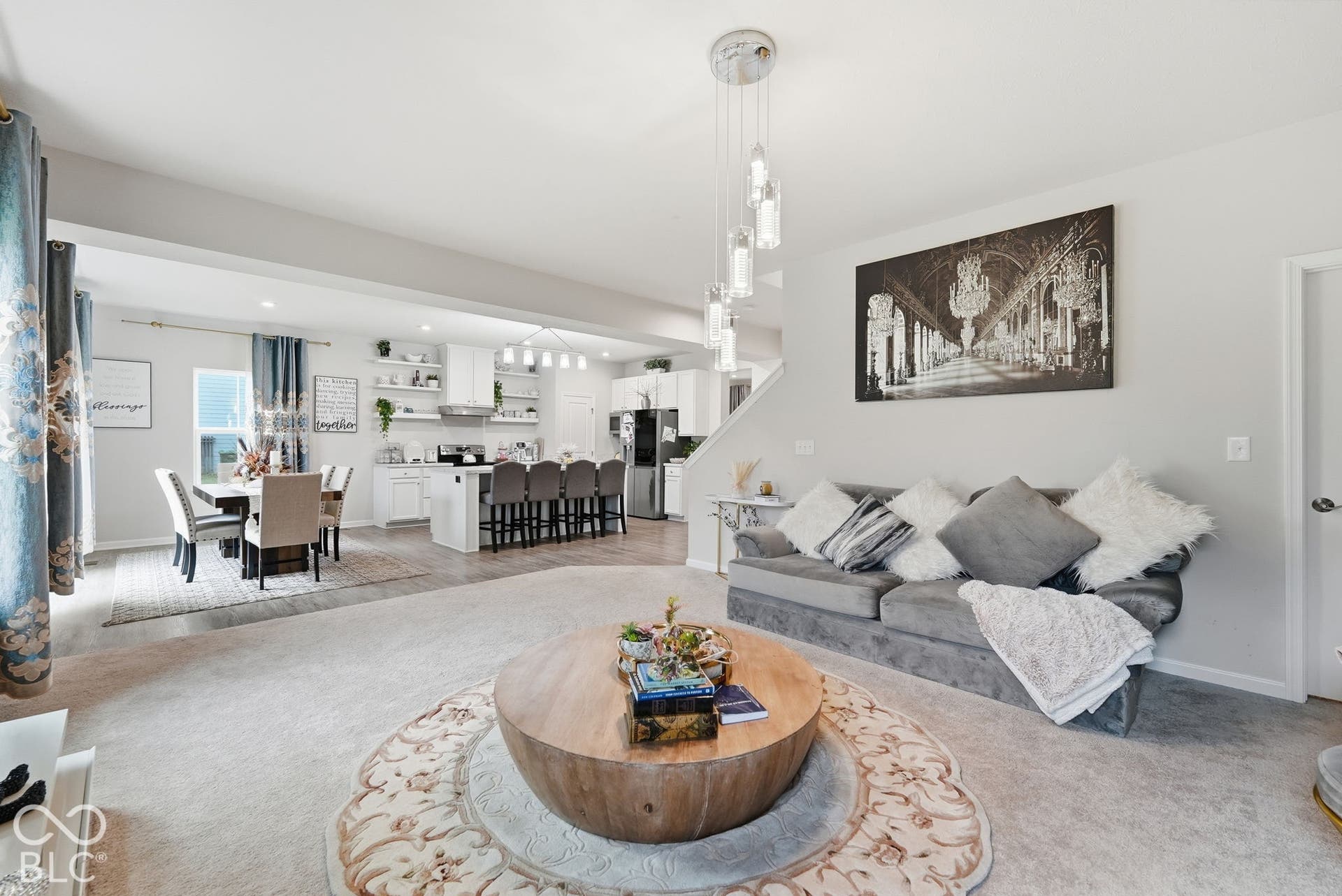 275 Bohicket Road, Whiteland, IN 46184 Open-concept living space featuring high ceilings, contemporary multi-pendant lighting, neutral carpeting, and a kitchen with white cabinetry and an island
