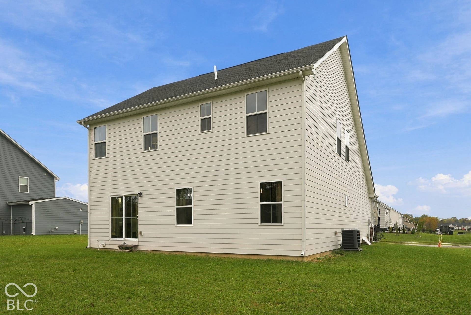 275 Bohicket Road, Whiteland, IN 46184 Two-story exterior featuring light-toned horizontal siding, a pitched roof, sliding glass patio door, and expansive lawn