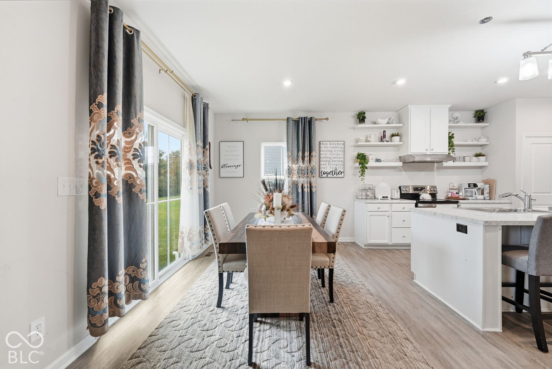 275 Bohicket Road, Whiteland, IN 46184 Kitchen featuring white shaker-style cabinetry, floating wall shelves, a center island with a stone-composite countertop, wood-finish flooring, and a glass sliding door
