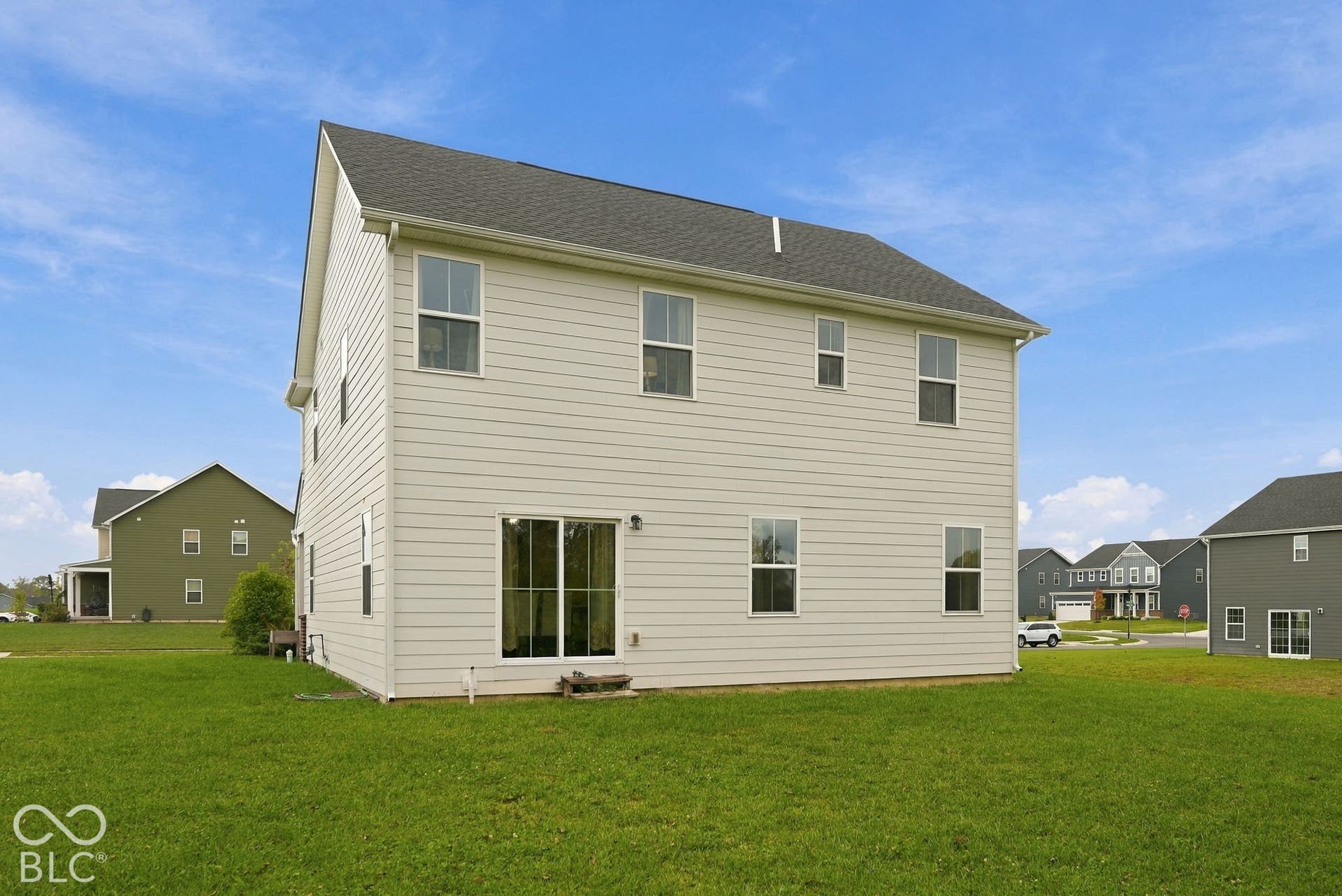 275 Bohicket Road, Whiteland, IN 46184 Rear elevation featuring light-colored horizontal siding, a pitched asphalt shingle roof, multiple grid-pattern windows, and a sliding glass door