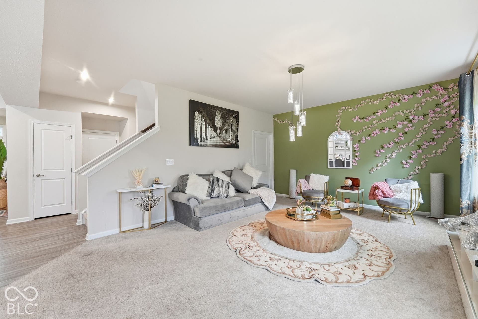 275 Bohicket Road, Whiteland, IN 46184 Neutral-toned living space featuring wall-to-wall carpeting, an architectural staircase with painted railings, and a multi-pendant light fixture