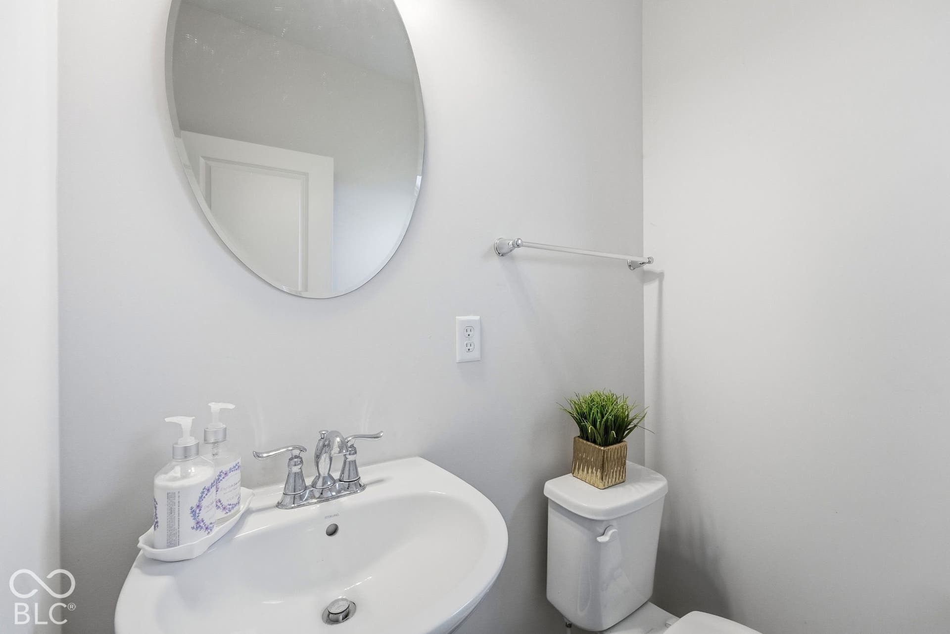 275 Bohicket Road, Whiteland, IN 46184 Oval wall-mounted mirror, pedestal sink with polished chrome hardware, and white porcelain toilet