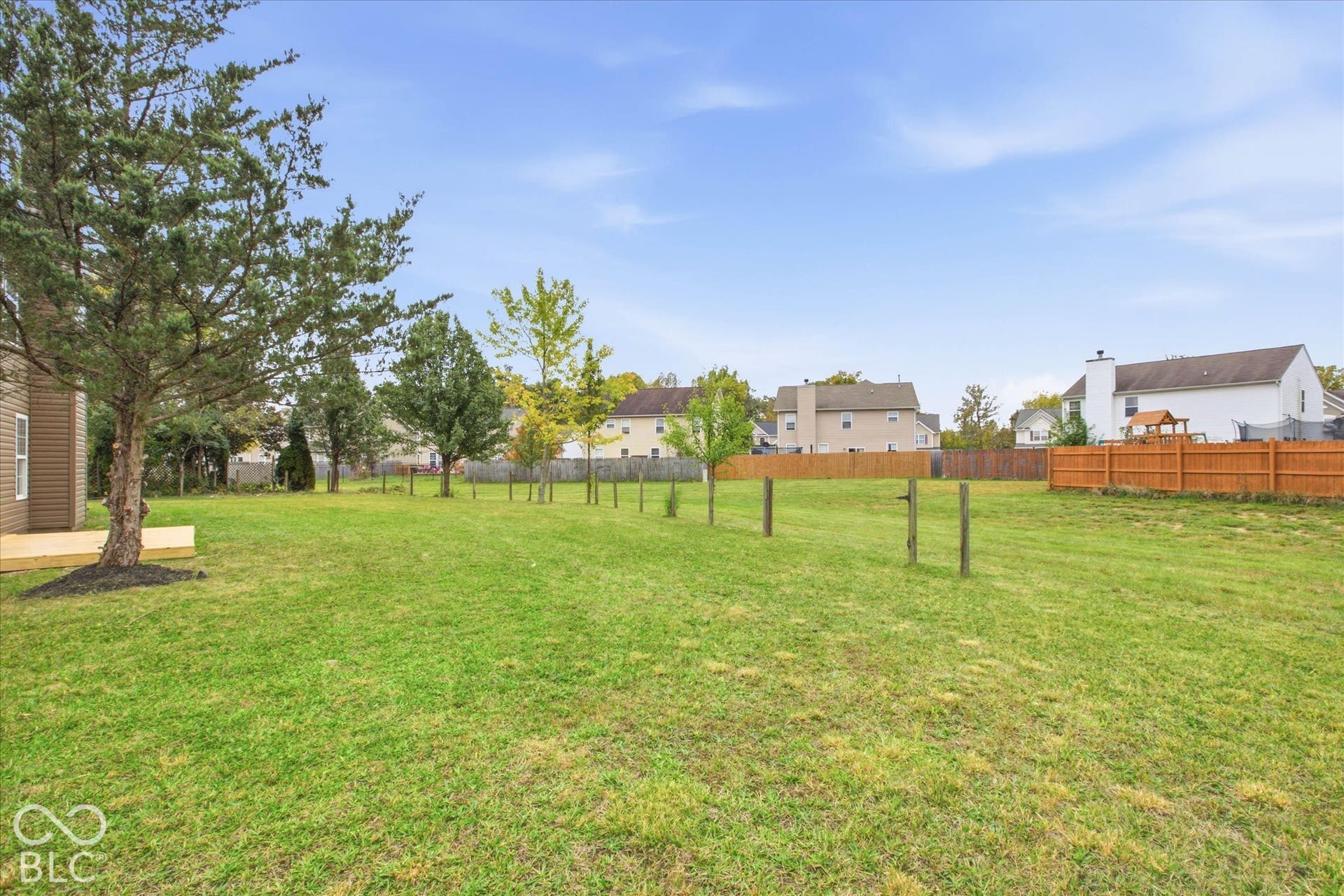 9607 Piper Lake Drive, Indianapolis, IN 46239 Expansive backyard featuring a manicured lawn, mature trees, wood-finish deck, and wood privacy fencing