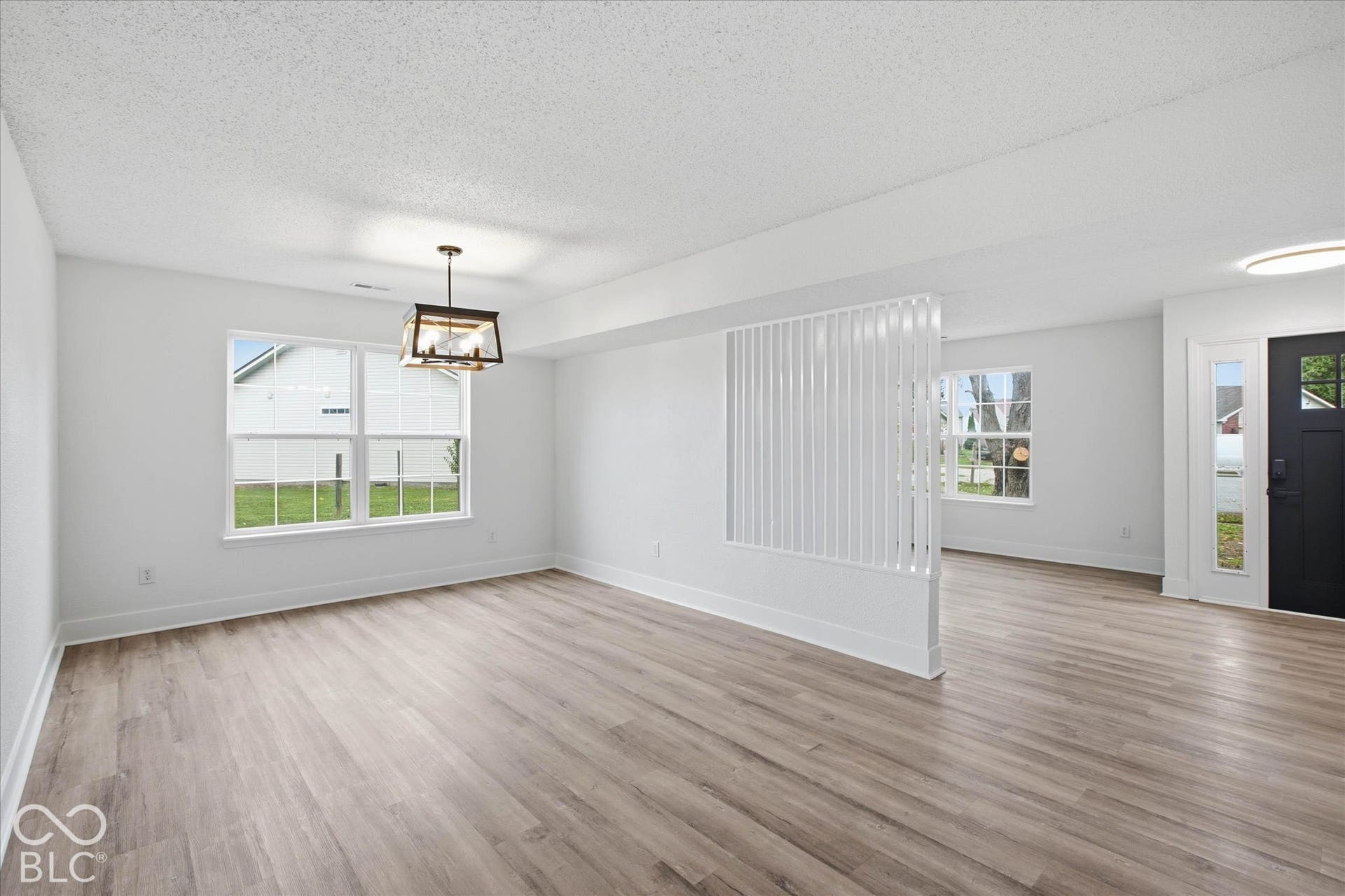 9607 Piper Lake Drive, Indianapolis, IN 46239 Interior space featuring wood-finish flooring, a decorative vertical slat room divider, a geometric pendant light fixture, and a dark-toned exterior entry door with glass pane detailing