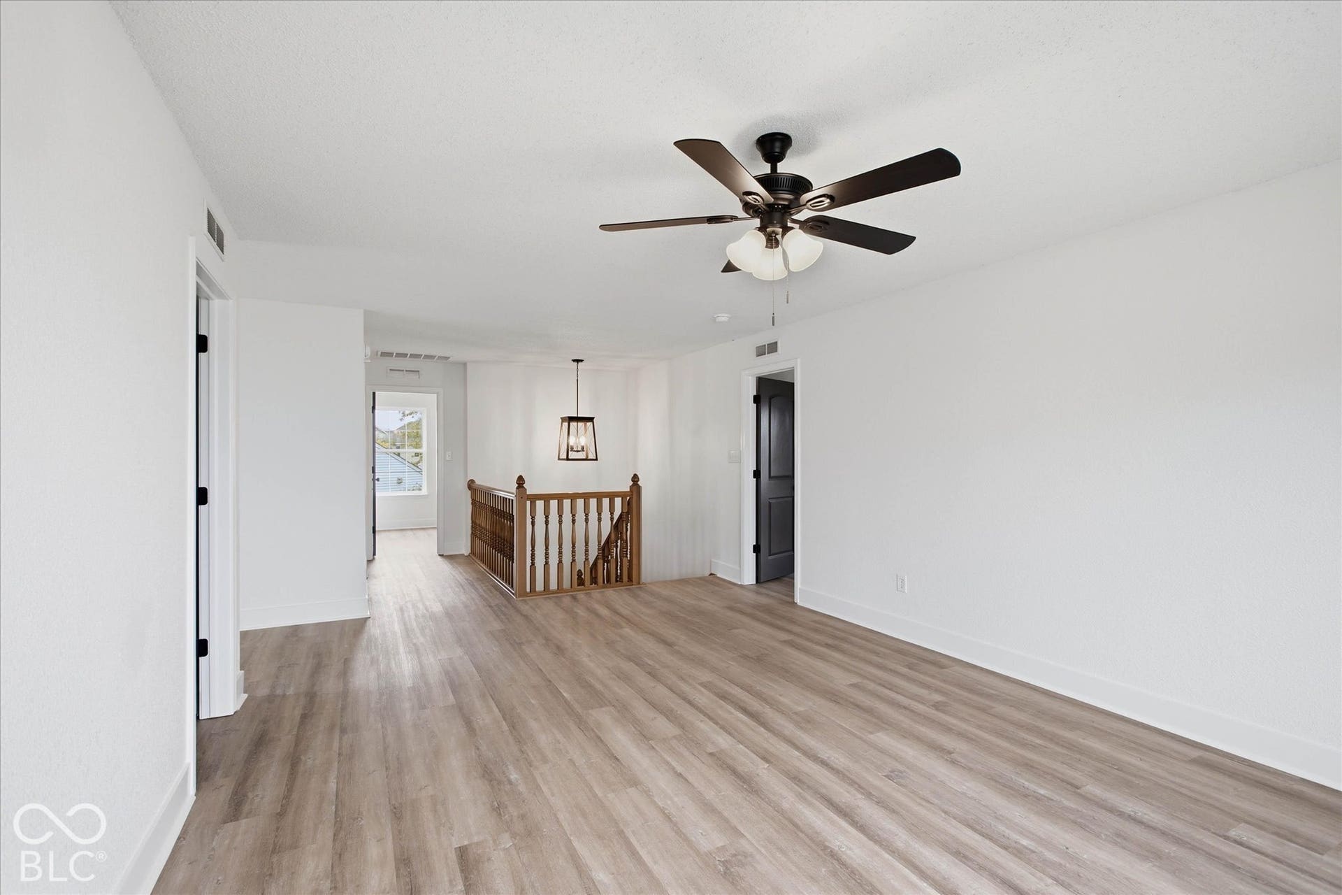 9607 Piper Lake Drive, Indianapolis, IN 46239 Wood-finish flooring, ceiling fan with integrated light fixture, and wooden staircase railing featuring decorative balusters