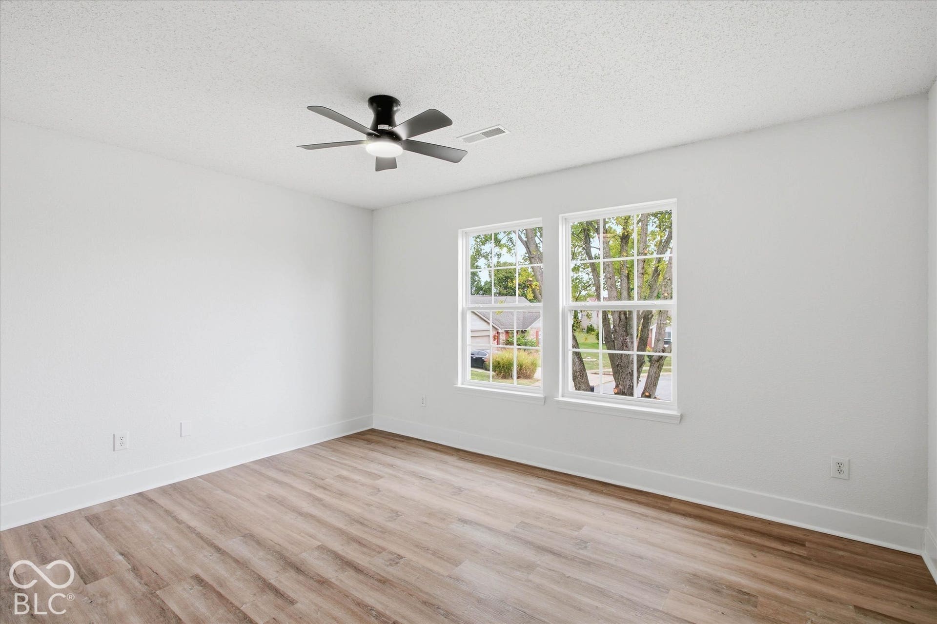 9607 Piper Lake Drive, Indianapolis, IN 46239 Room featuring wood-finish flooring, dual windows with white trim, and a matte black ceiling fan with integrated lighting