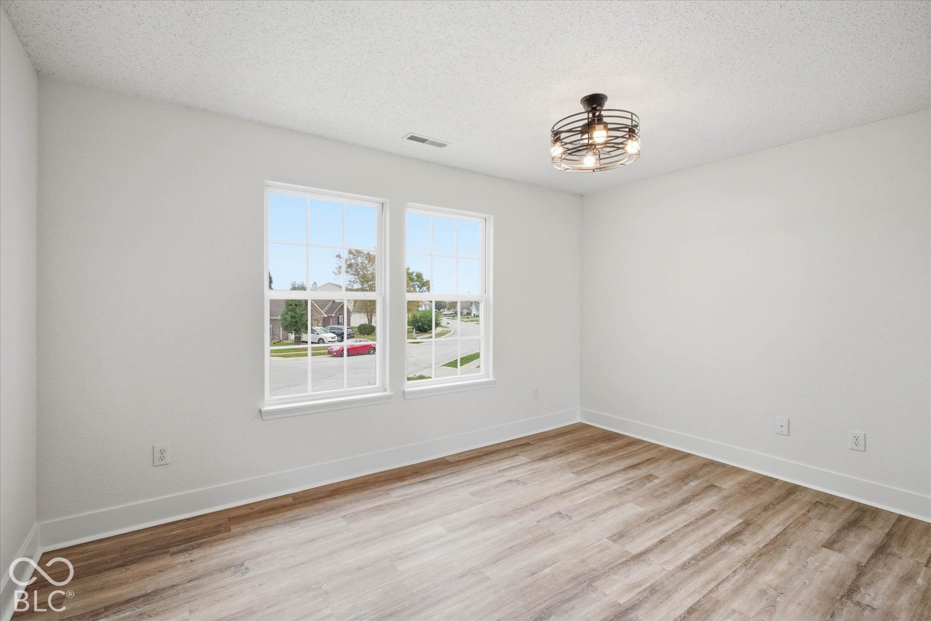 9607 Piper Lake Drive, Indianapolis, IN 46239 Room featuring wood-finish flooring, dual windows with muntins, and a geometric metal cage semi-flush mount light fixture