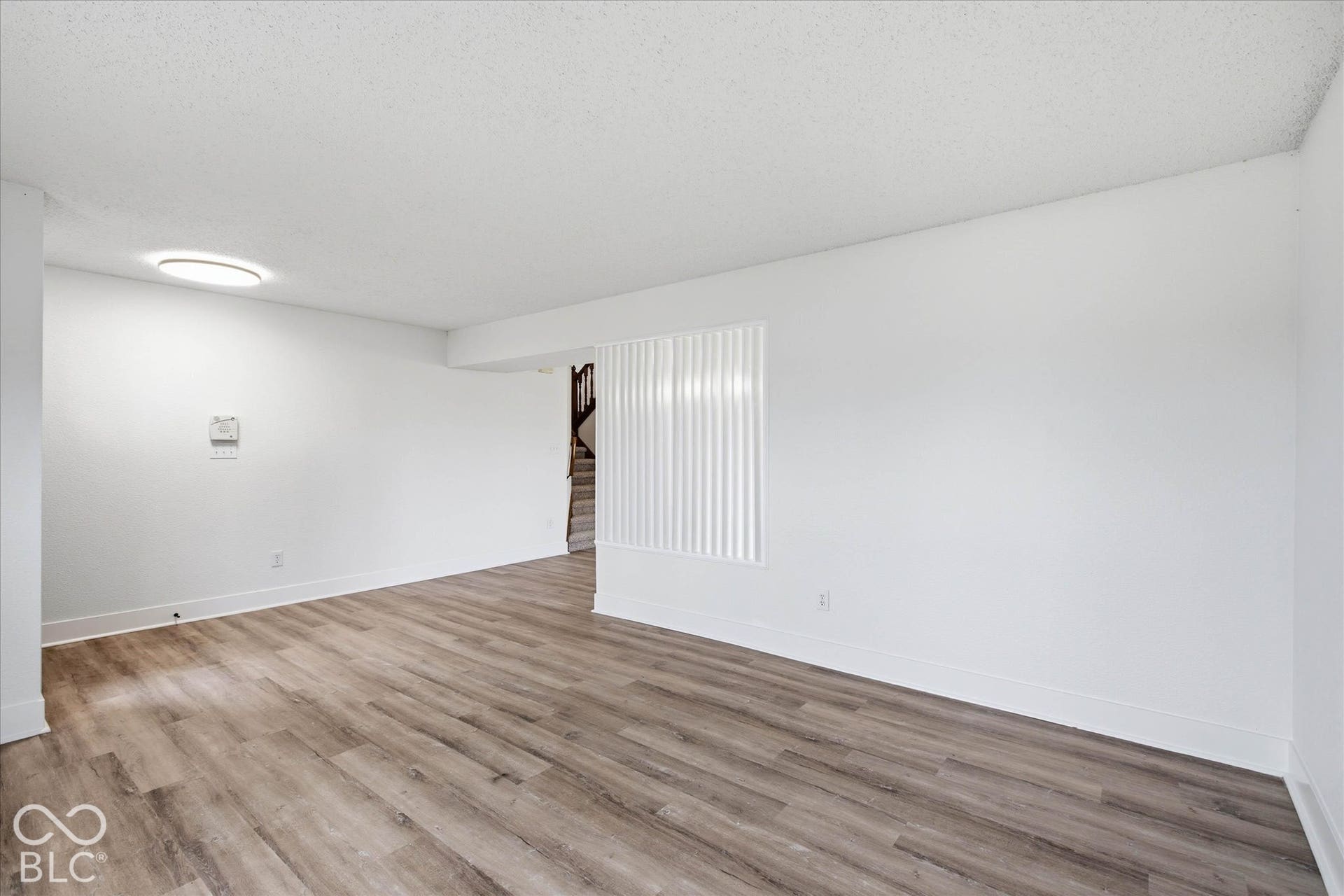 9607 Piper Lake Drive, Indianapolis, IN 46239 Neutral-toned interior featuring wood-finish flooring, crisp white wall finishes, and a flush-mount circular ceiling light fixture