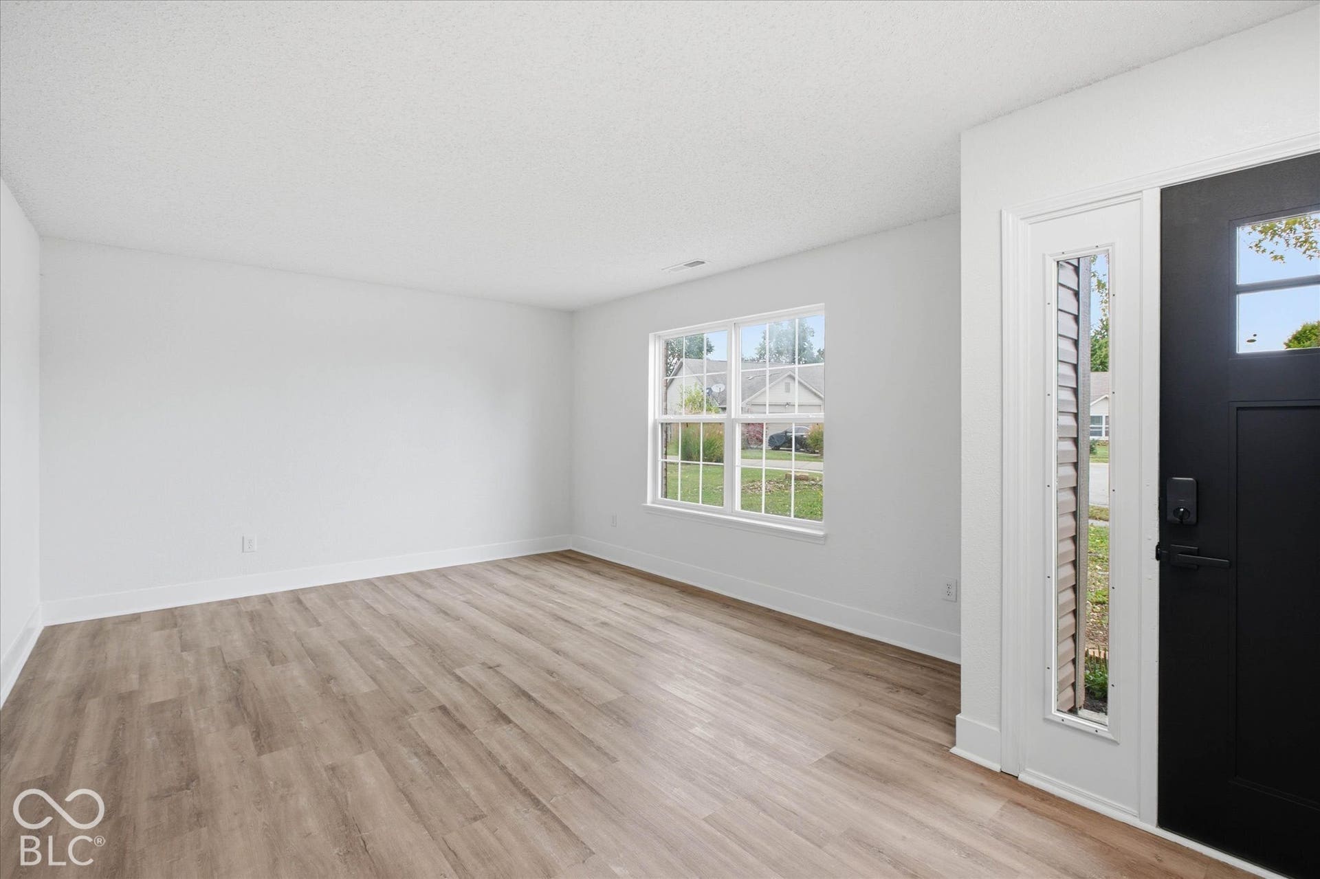 9607 Piper Lake Drive, Indianapolis, IN 46239 Neutral-toned wall finish, wood-finish flooring, multi-pane window, and exterior door with a vertical glass insert