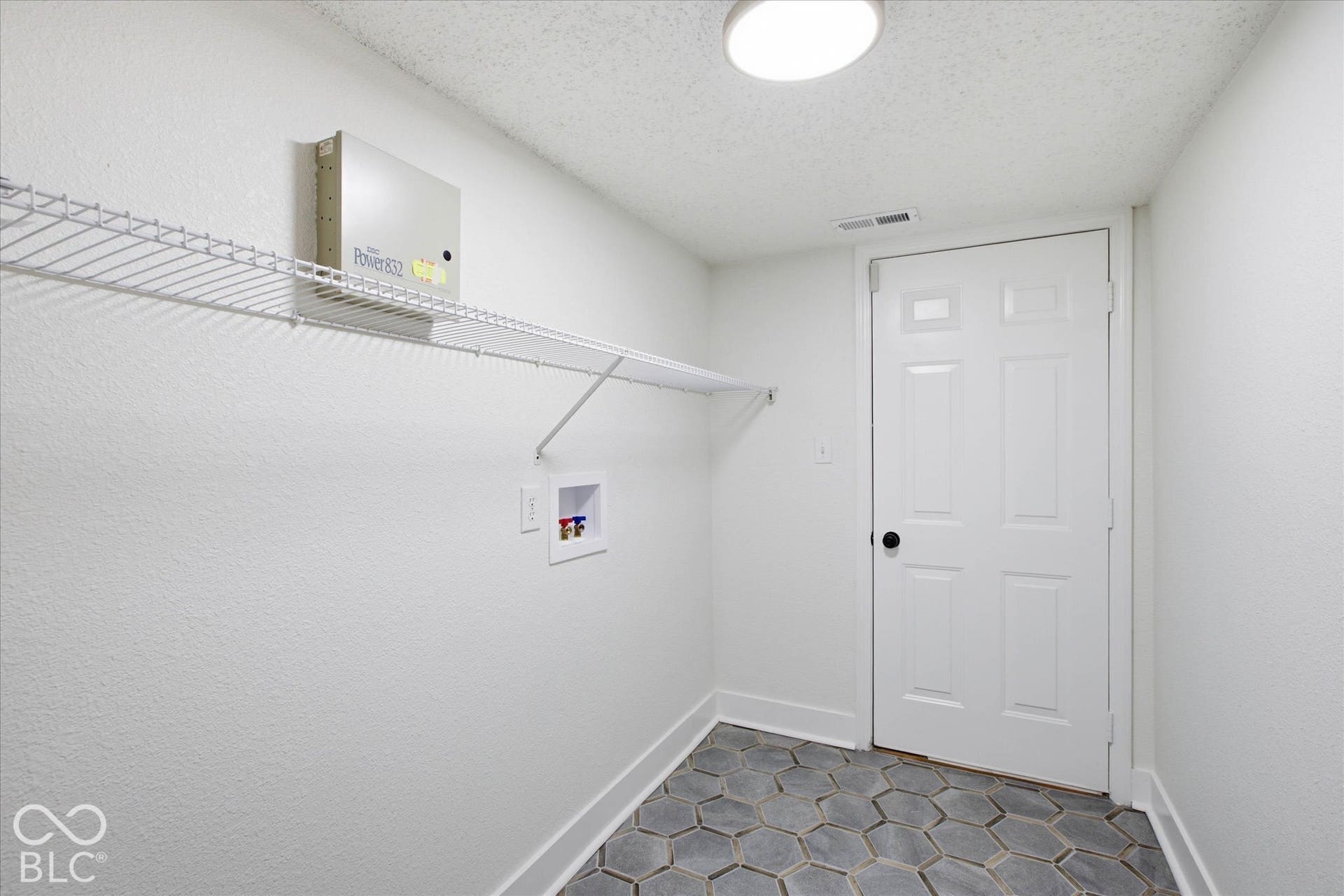 9607 Piper Lake Drive, Indianapolis, IN 46239 Utility area featuring hexagonal tile flooring, wall-mounted wire shelving, and recessed laundry hookups with a white six-panel interior door