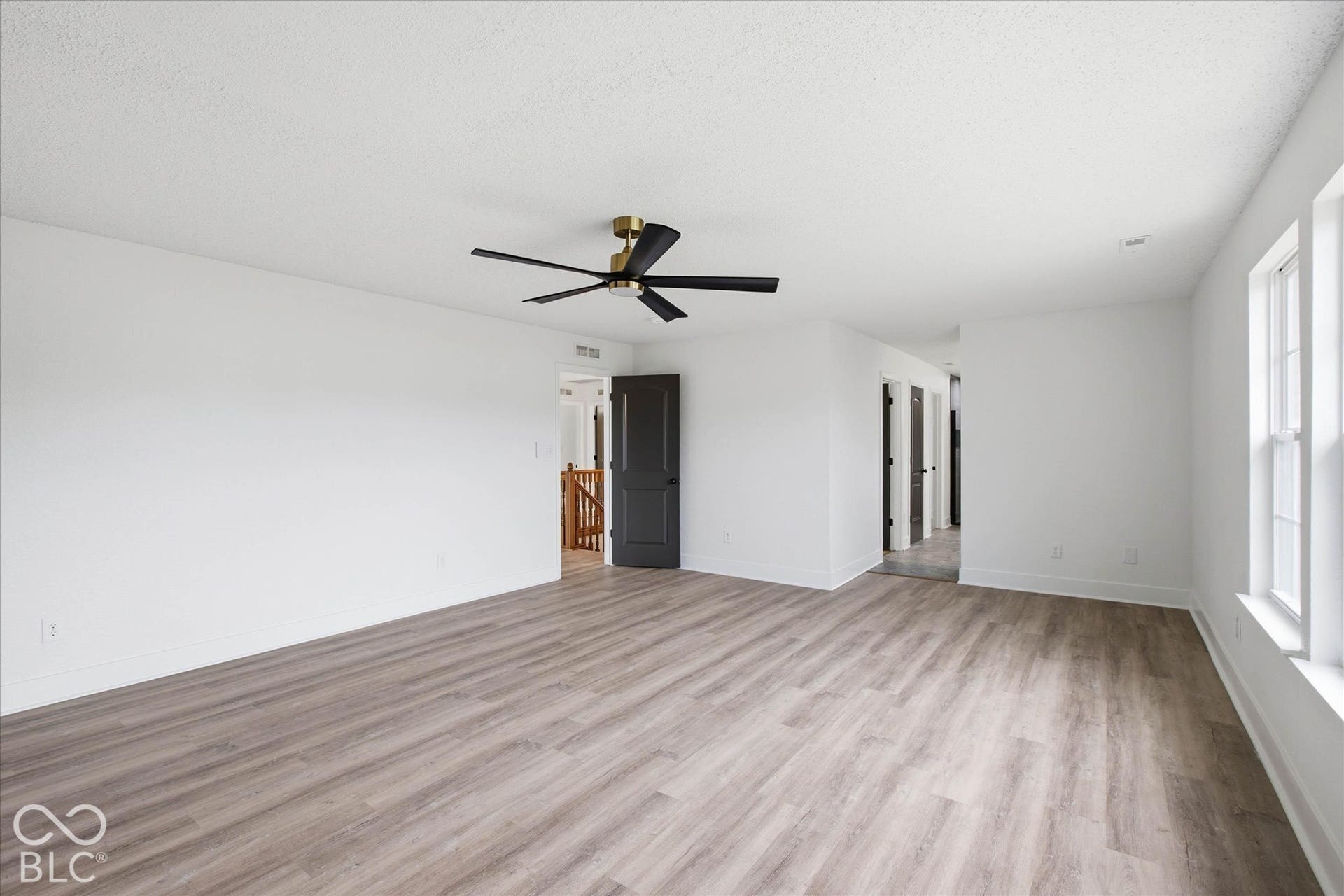 9607 Piper Lake Drive, Indianapolis, IN 46239 Spacious room featuring wood-finish flooring, a modern matte black ceiling fan, white walls, and contrasting matte black interior doors