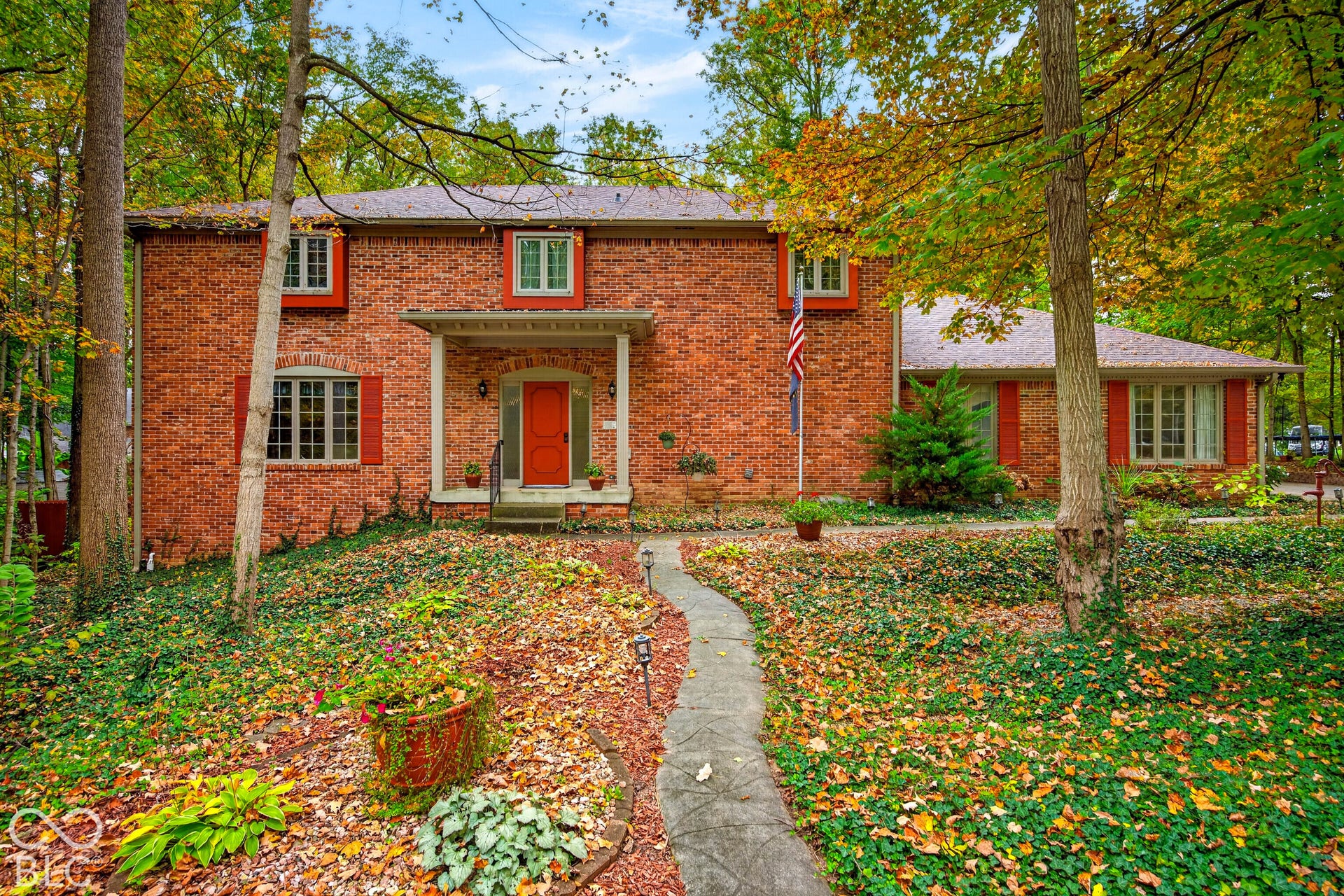 Two-story brick exterior featuring a covered front entryway, multi-pane windows with contrasting shutters, and a stone-paver walkway