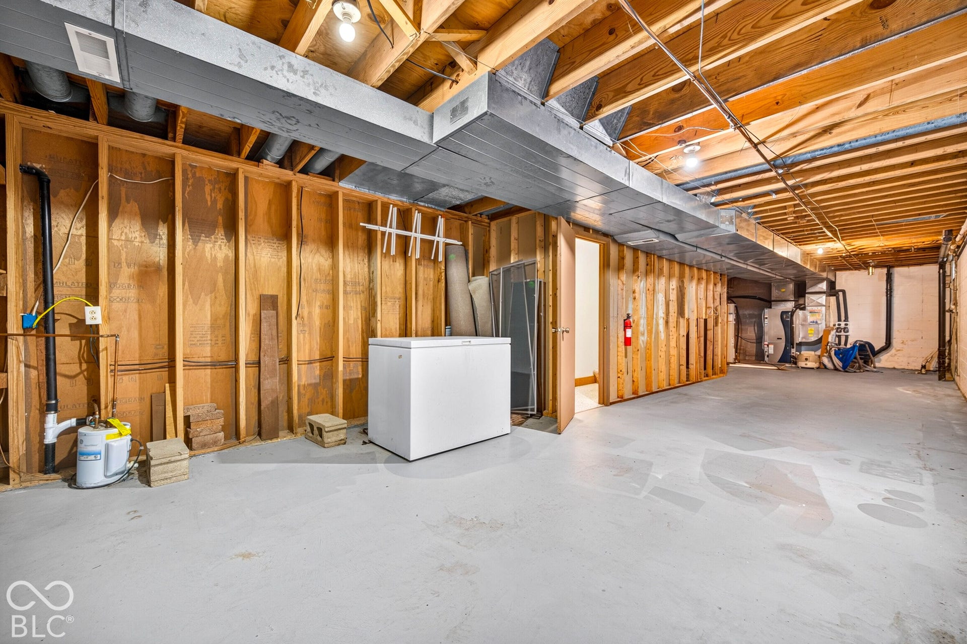 Unfinished lower level featuring exposed wood framing, painted concrete flooring, metallic ductwork, and exposed ceiling joists