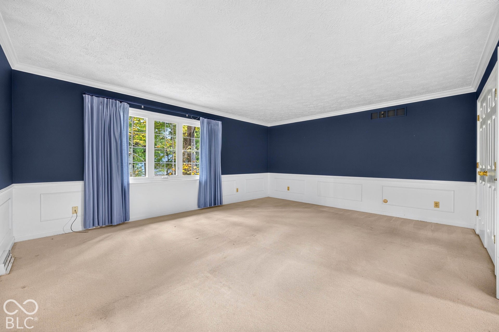Interior space featuring white wainscoting, multi-pane window, and six-panel interior door