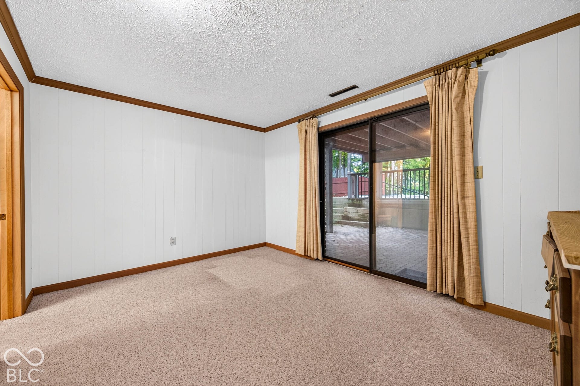 Interior space featuring wall-to-wall carpeting, wood-finish trim, and sliding glass doors leading to a covered patio