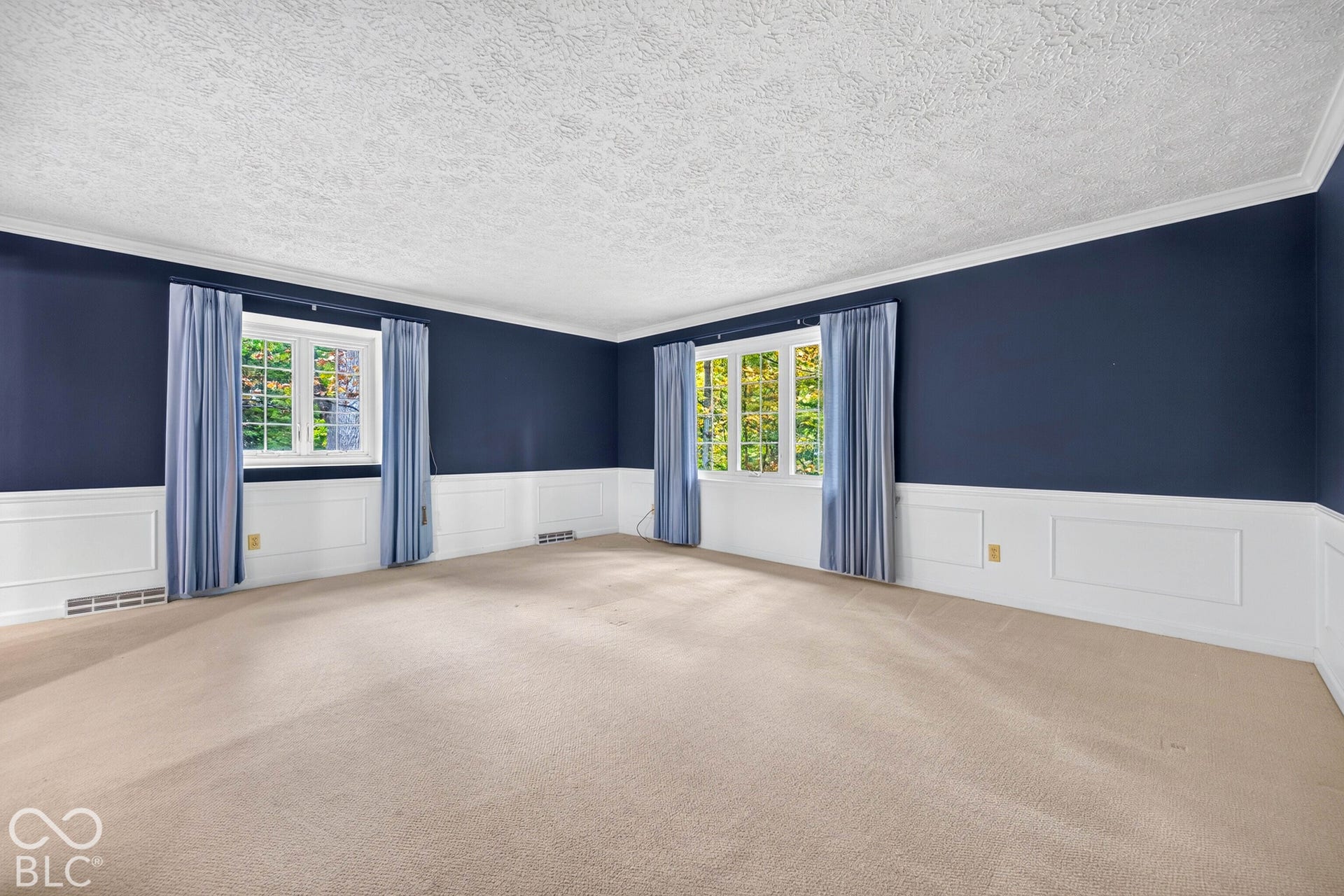 Room featuring crown molding, extensive white wainscoting, multi-pane windows, and neutral carpeting