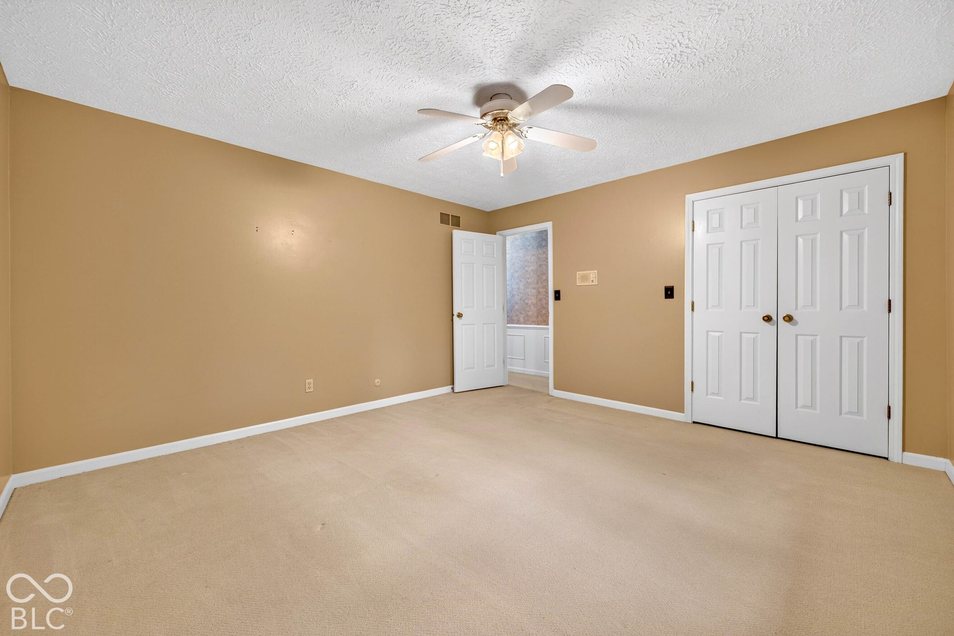 Room featuring carpeted flooring, a ceiling fan with integrated lighting, and a double-door closet with panelled doors