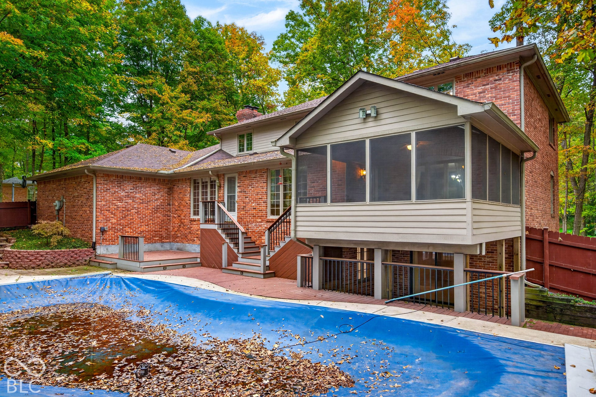 Brick exterior featuring a multi-level deck, screened-in porch, built-in swimming pool, and retaining wall