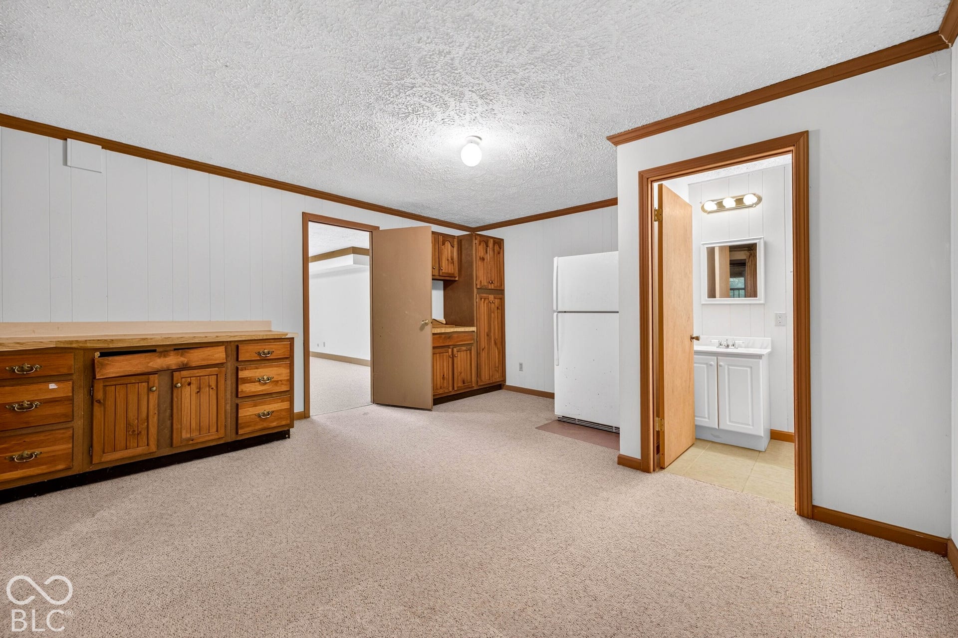 Built-in wood cabinetry with storage drawers, white-finish refrigerator, and carpeted flooring
