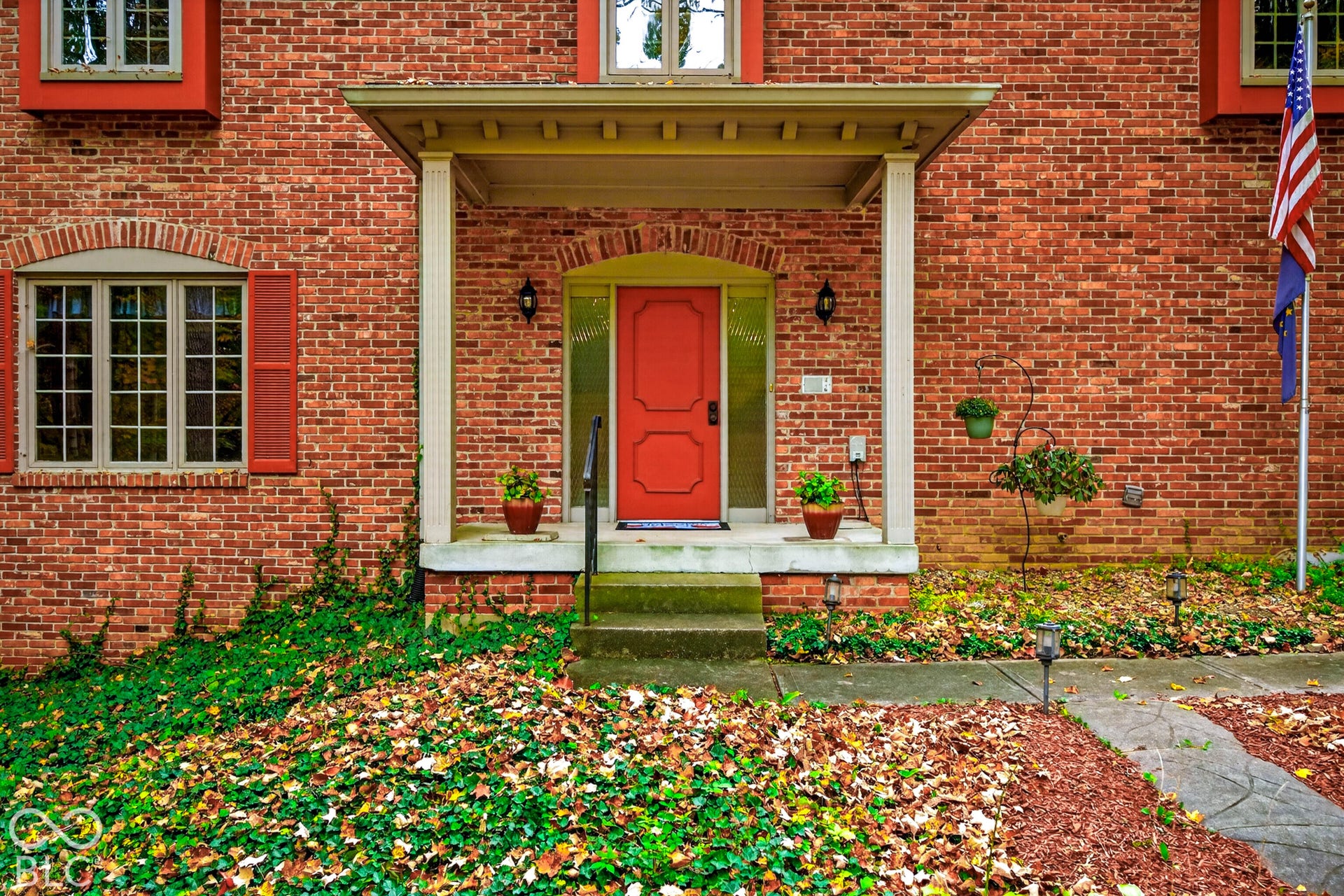 Brick facade exterior featuring a covered front porch, paneled door with sidelights, arched window detailing, and decorative shutters