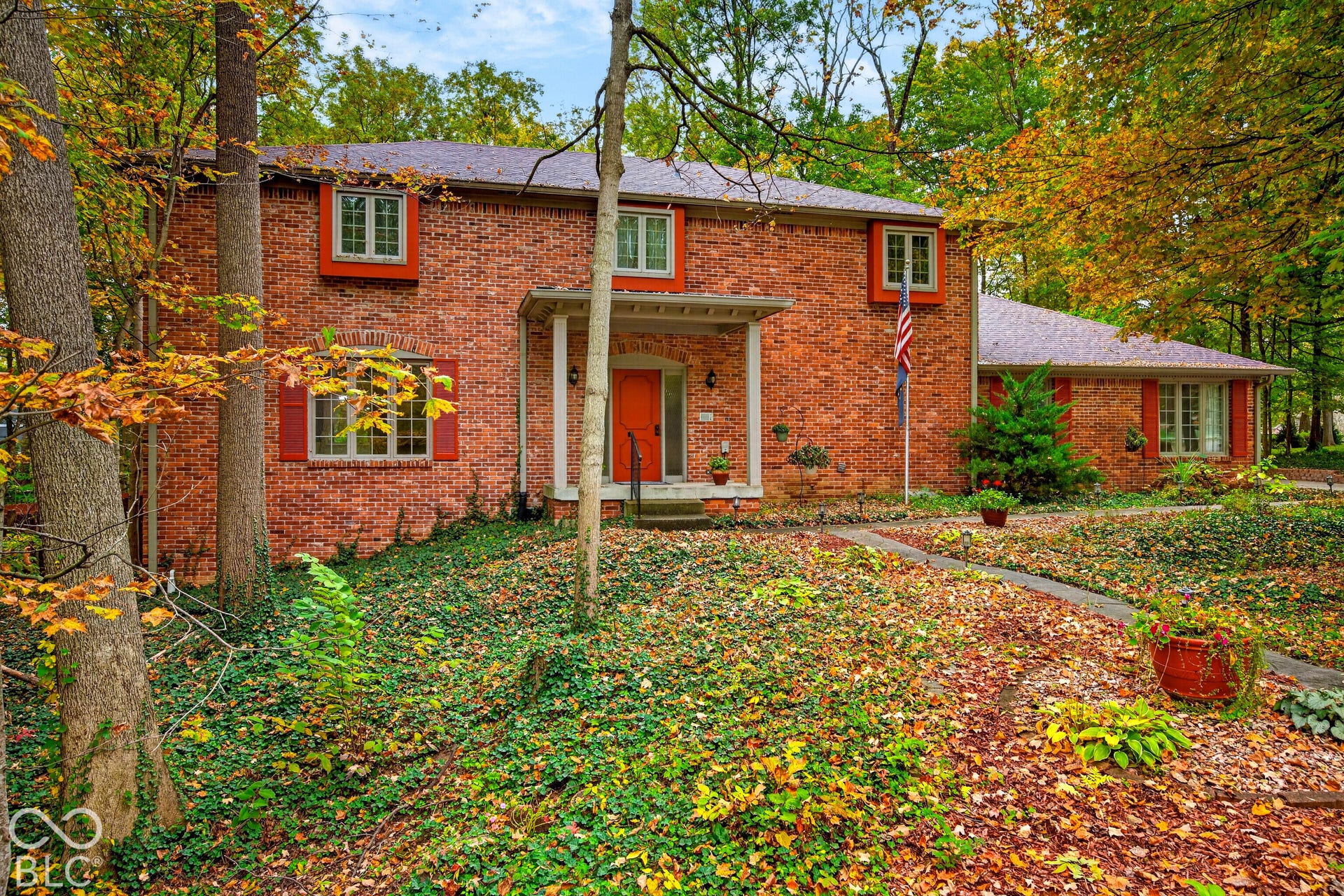 Multi-level brick exterior featuring a covered front entryway, shuttered window accents, and a paved walkway