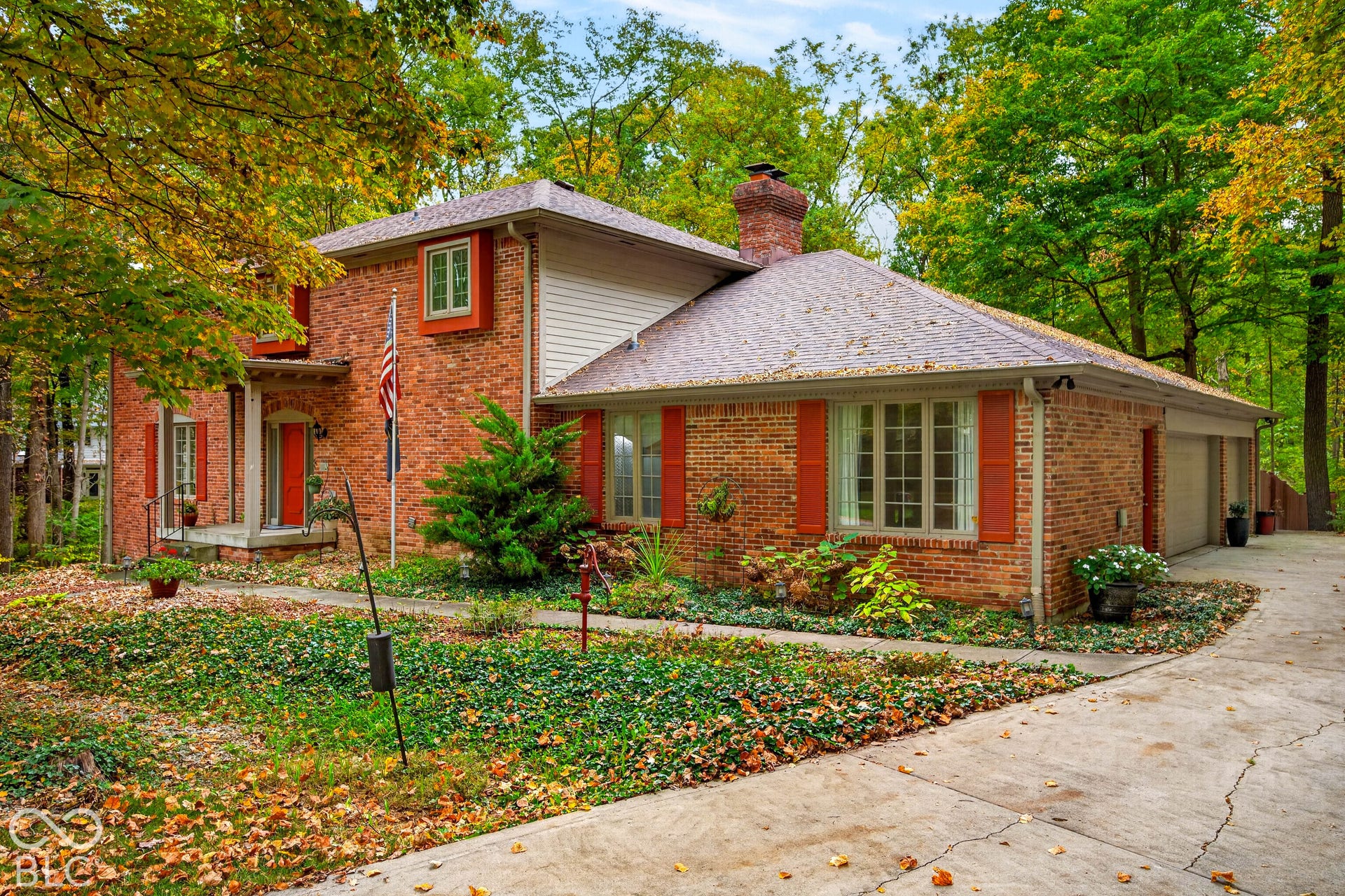 Two-story brick exterior featuring a multi-gabled roofline, brick chimney, shuttered multi-pane windows, and an attached multi-car garage