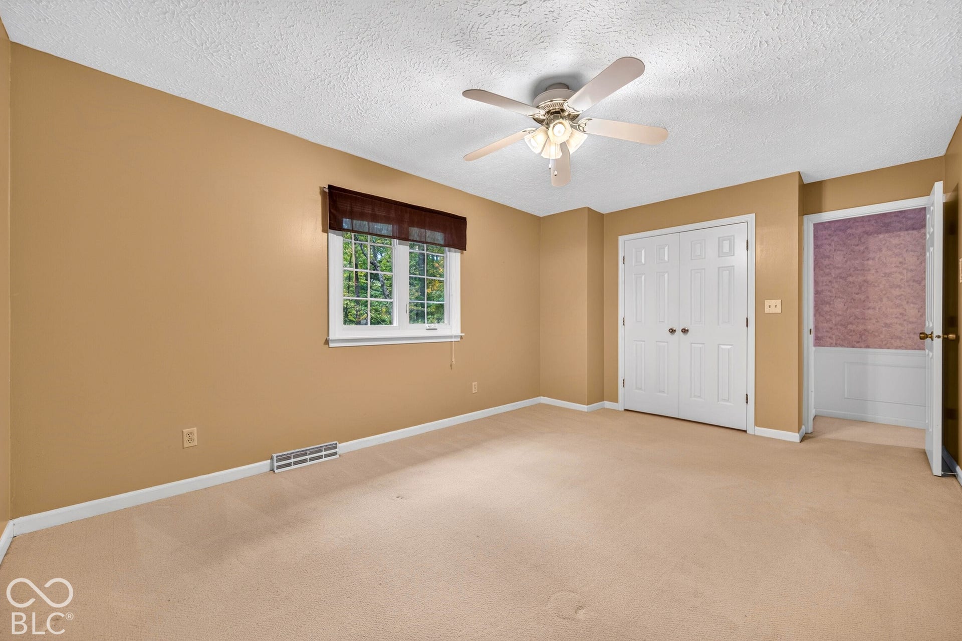 Room featuring wall-to-wall carpeting, ceiling fan with integrated lighting, multi-pane window, and double-door closet