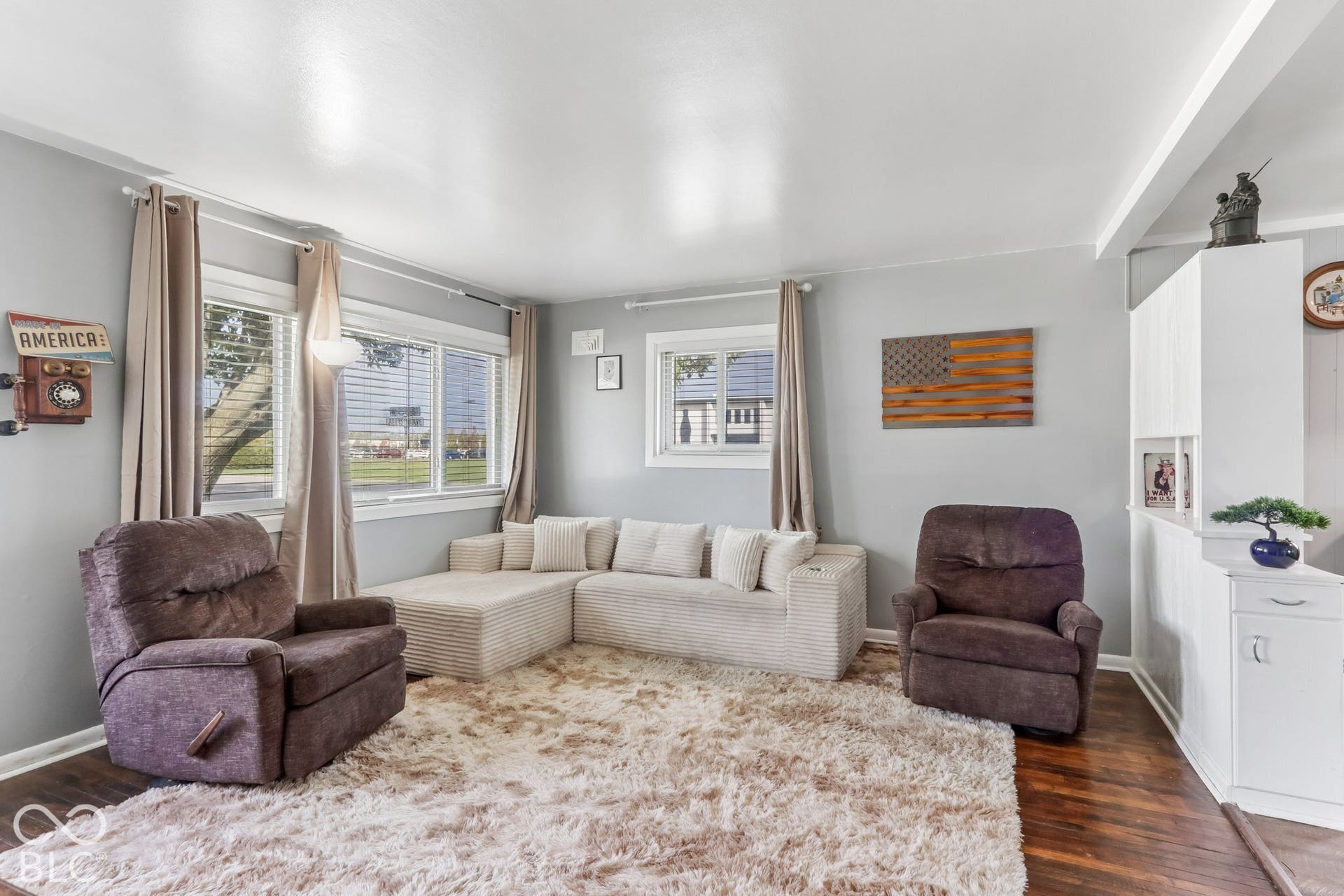 Living area featuring wood-finish flooring, multi-pane windows, and built-in white cabinetry with a partition wall