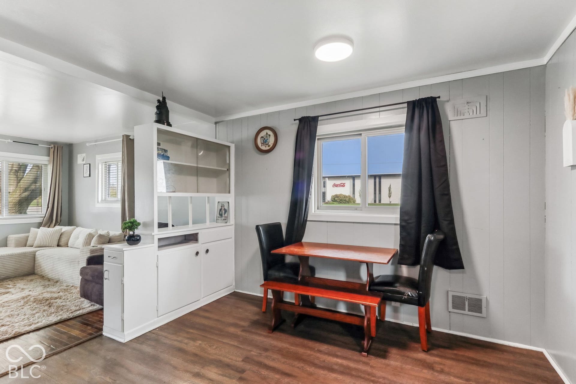 Interior space featuring wood-finish flooring, a white built-in shelving unit with lower cabinetry, and a dual-pane sliding window