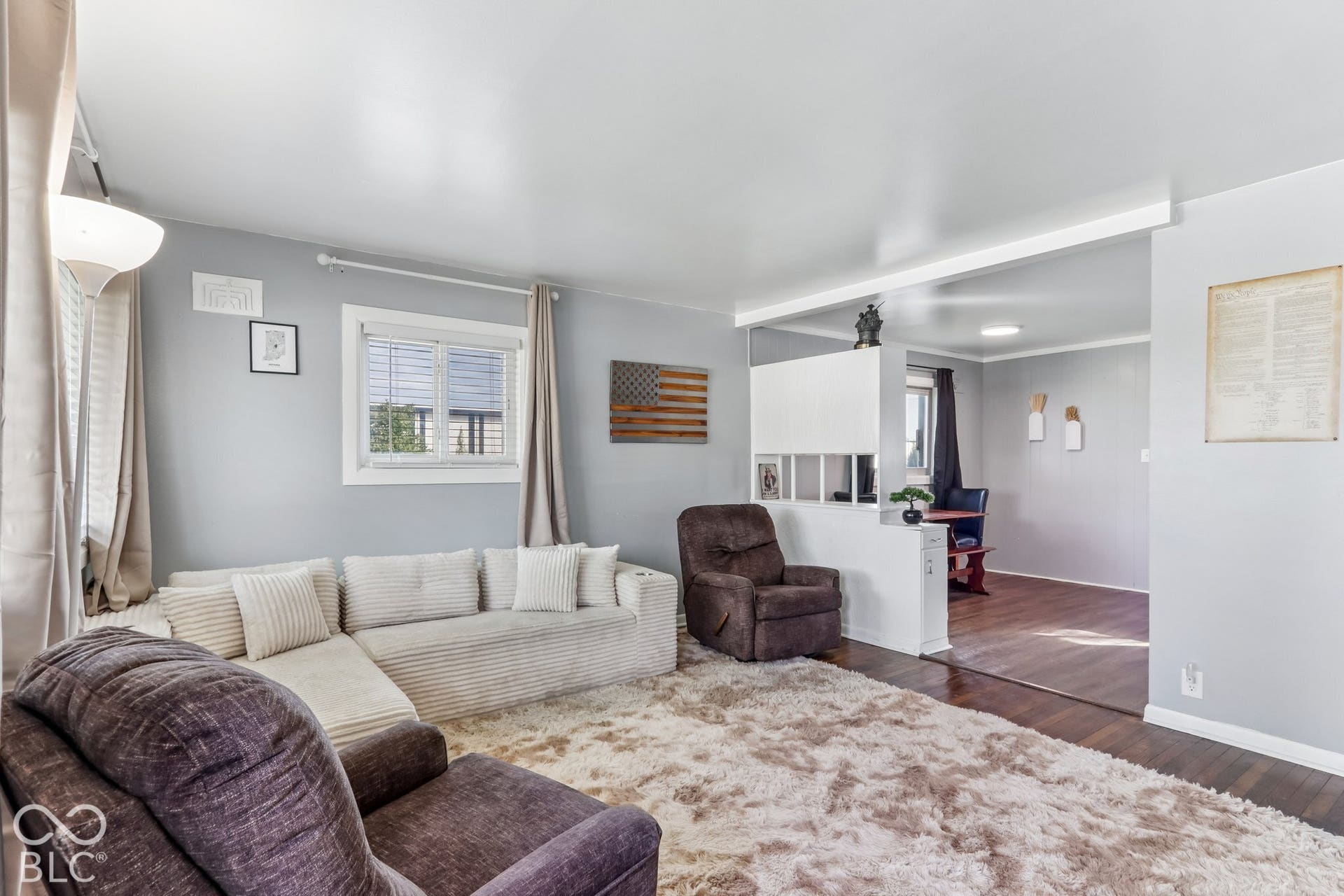 Living area featuring neutral wall paint, wood-finish flooring, and a half-height partition wall with built-in lower cabinetry