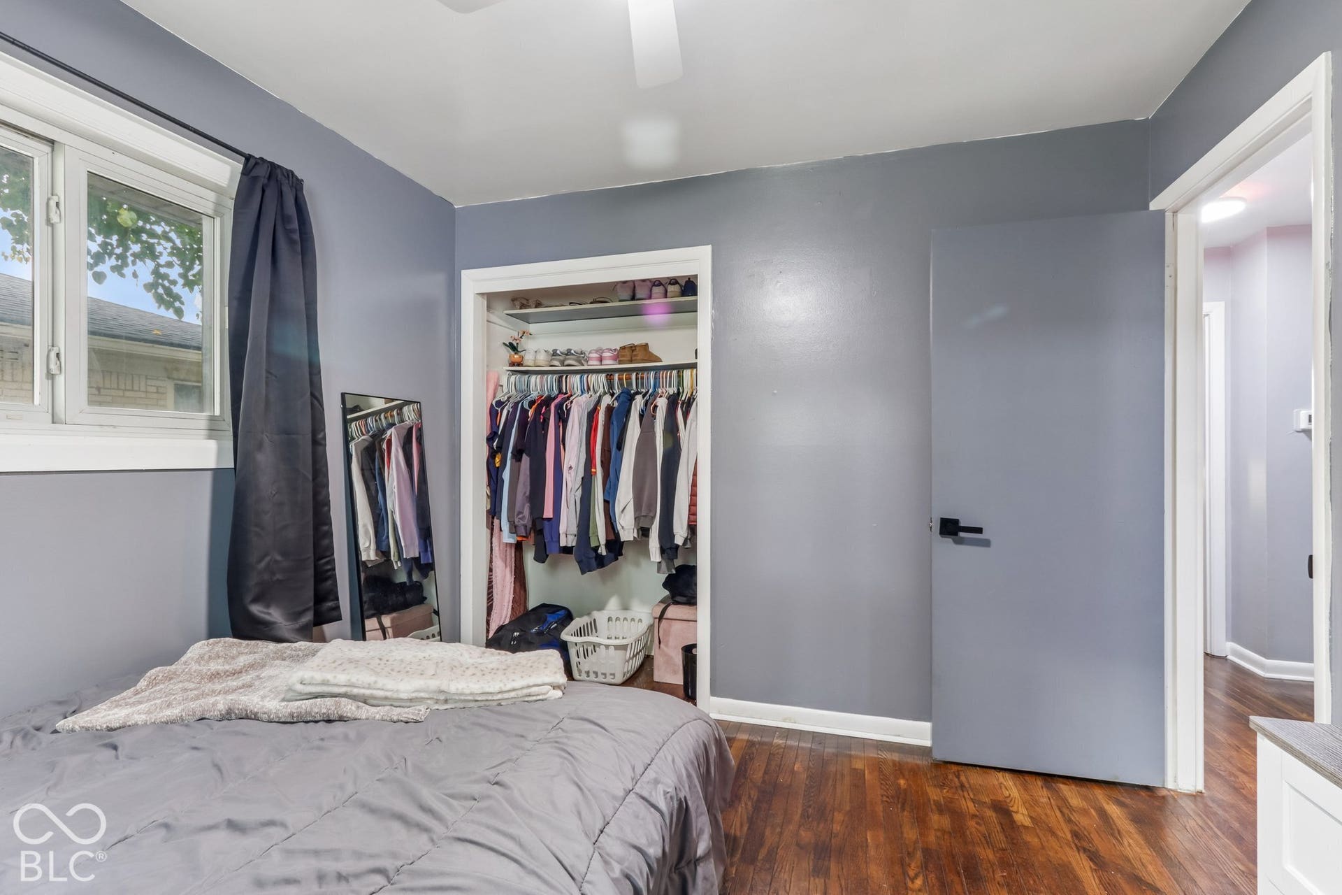 Wood-finish flooring, closet with built-in shelving, solid-core door with matte black hardware, and dual-pane window
