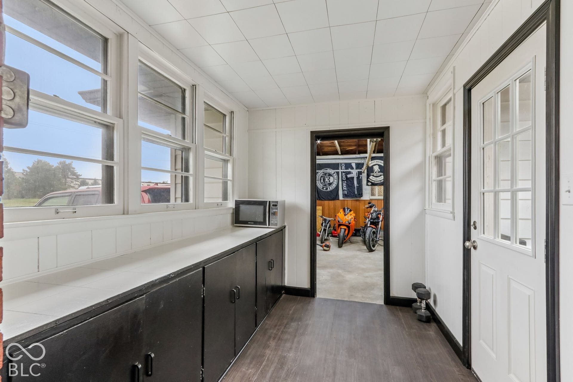 Enclosed porch featuring wood-finish flooring, extensive built-in cabinetry with white countertops, and multiple windows