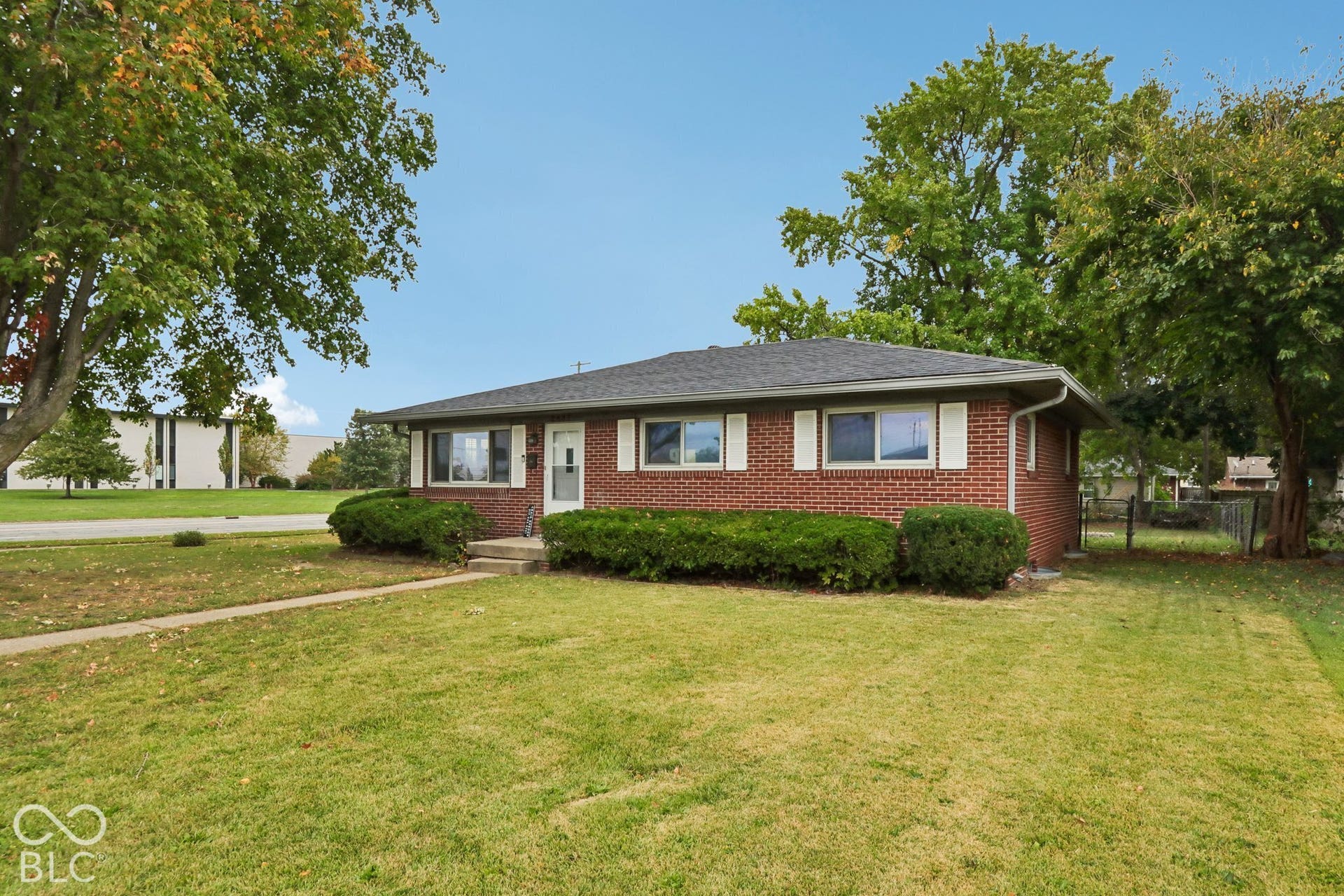 Single-story ranch exterior featuring a classic red brick facade, low-pitch hip roof, and decorative window shutters