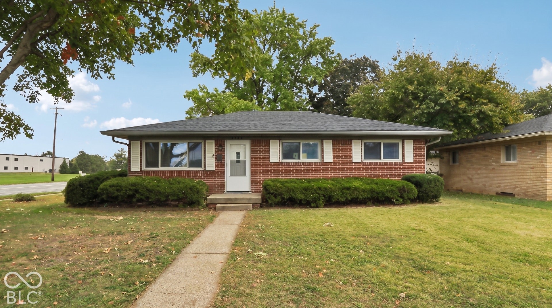 Single-story brick exterior featuring a hip roof, horizontal sliding windows with white shutters, and a central entryway with a concrete stoop