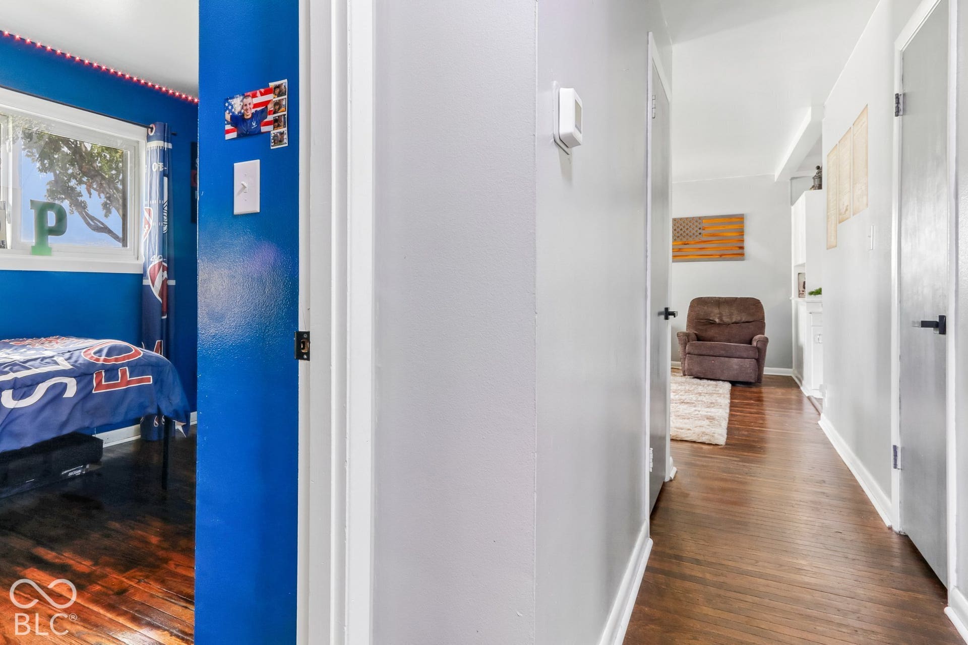 Hallway featuring wood-finish flooring and solid-core interior doors with matte black hardware