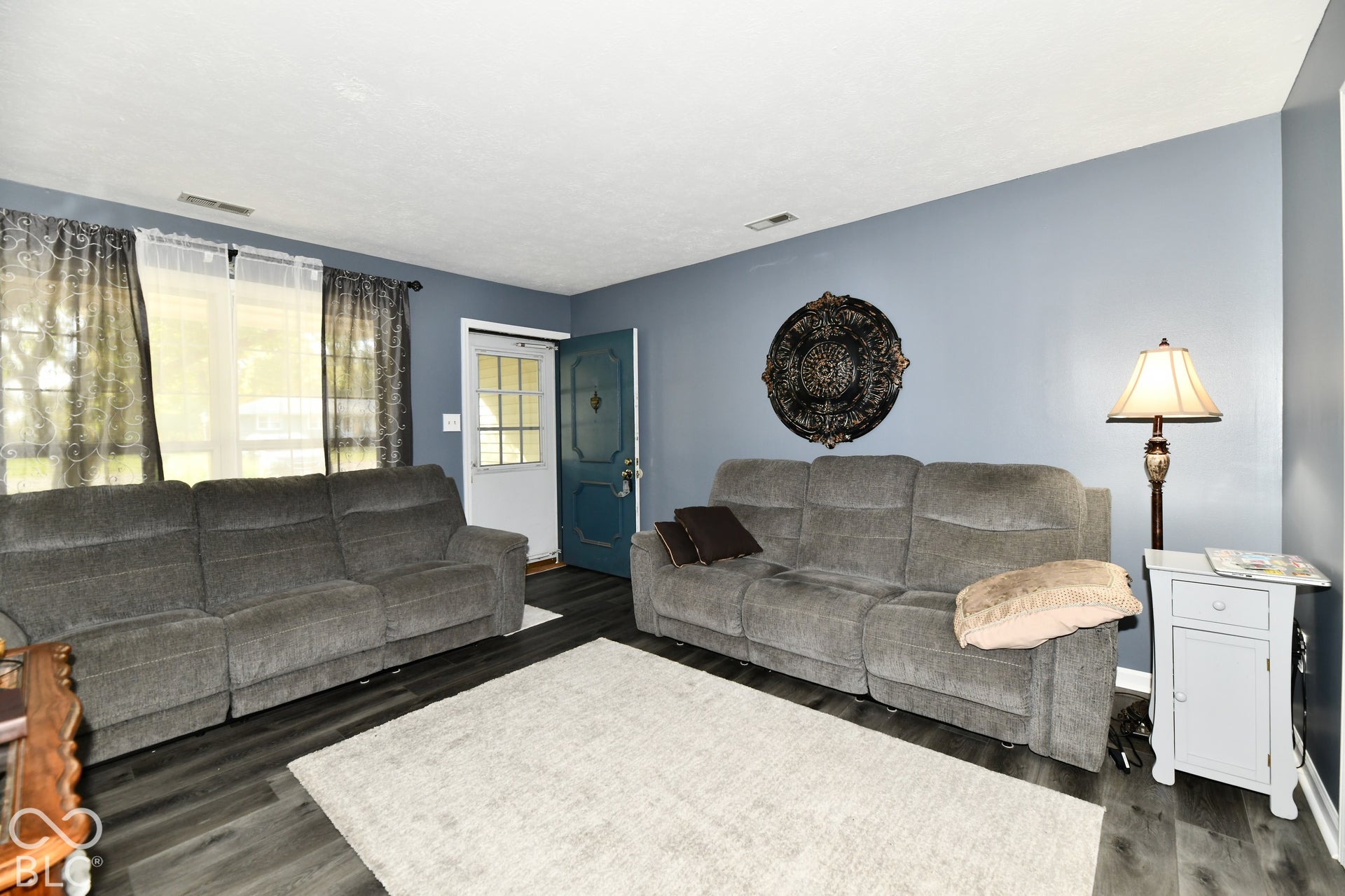 Living area featuring wood-finish flooring, a multi-pane entry door, and large window with exterior exposure