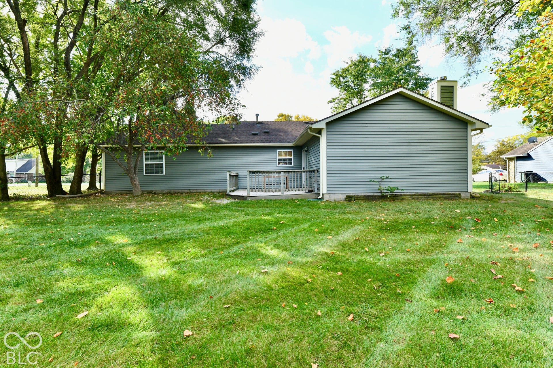 Backyard featuring horizontal siding, a wooden deck, and mature trees