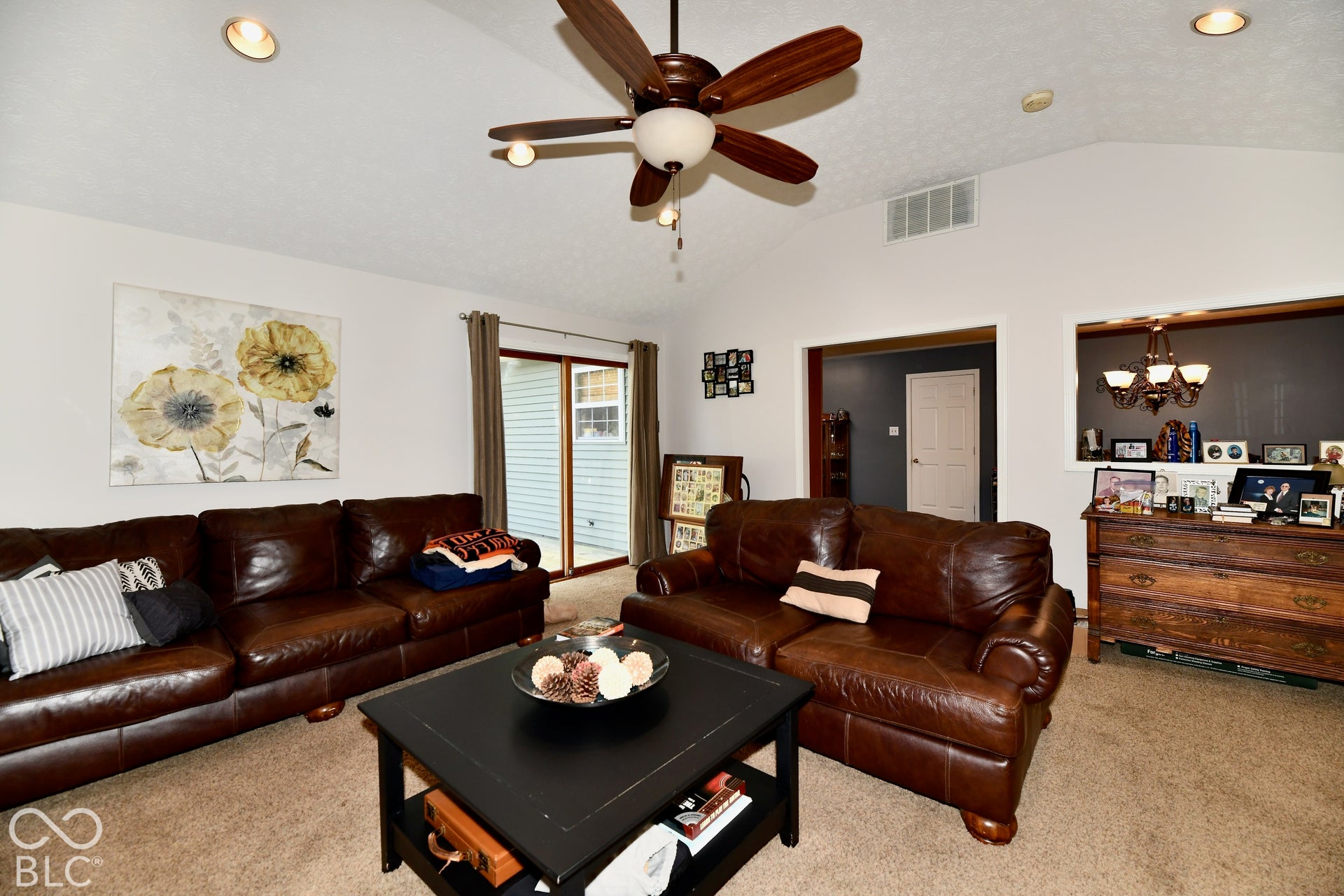 Vaulted ceiling, multi-blade ceiling fan with integrated light fixture, and sliding glass door