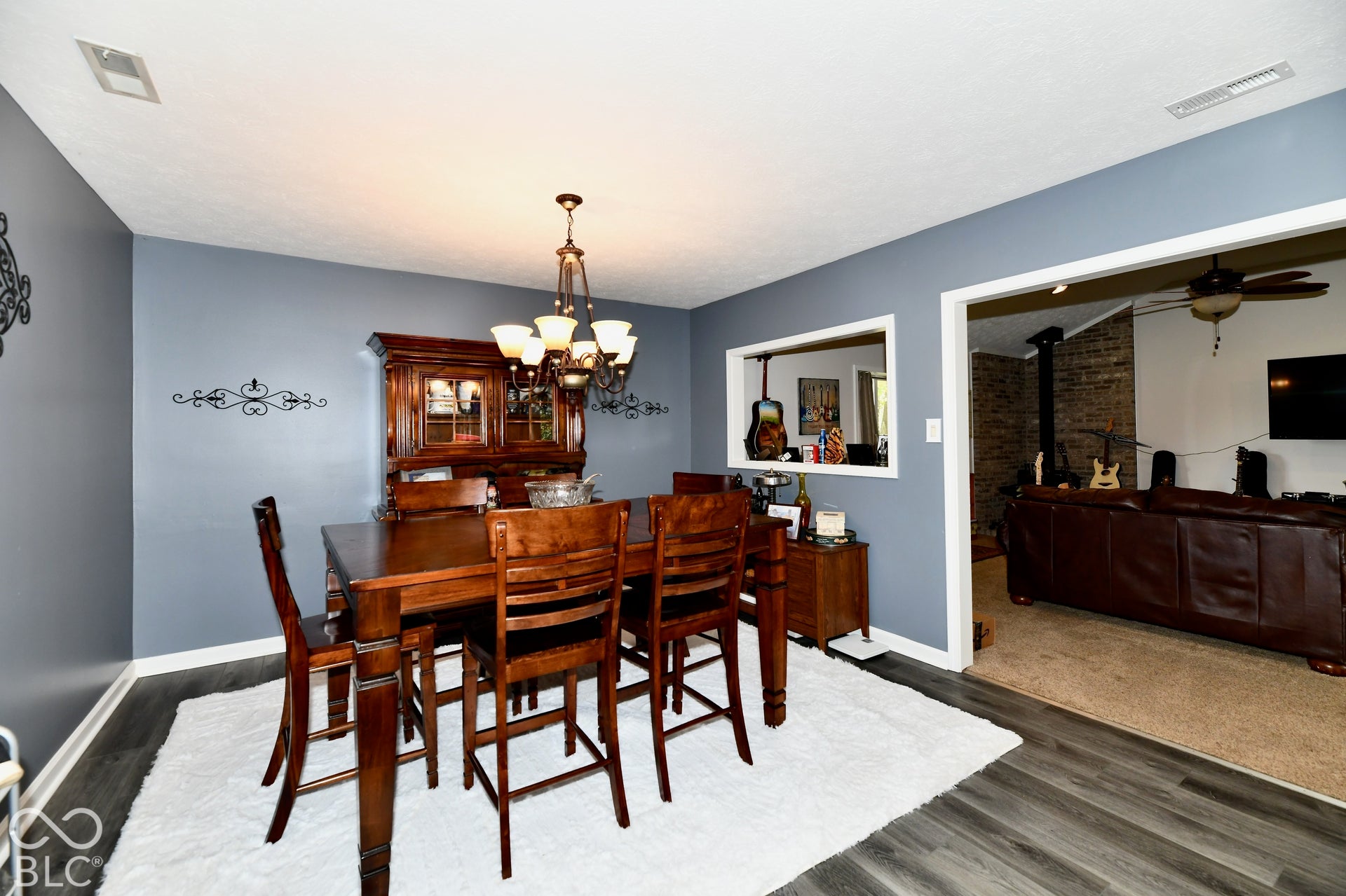 Dining area featuring wood-finish flooring, a multi-light chandelier, and a decorative wall pass-through