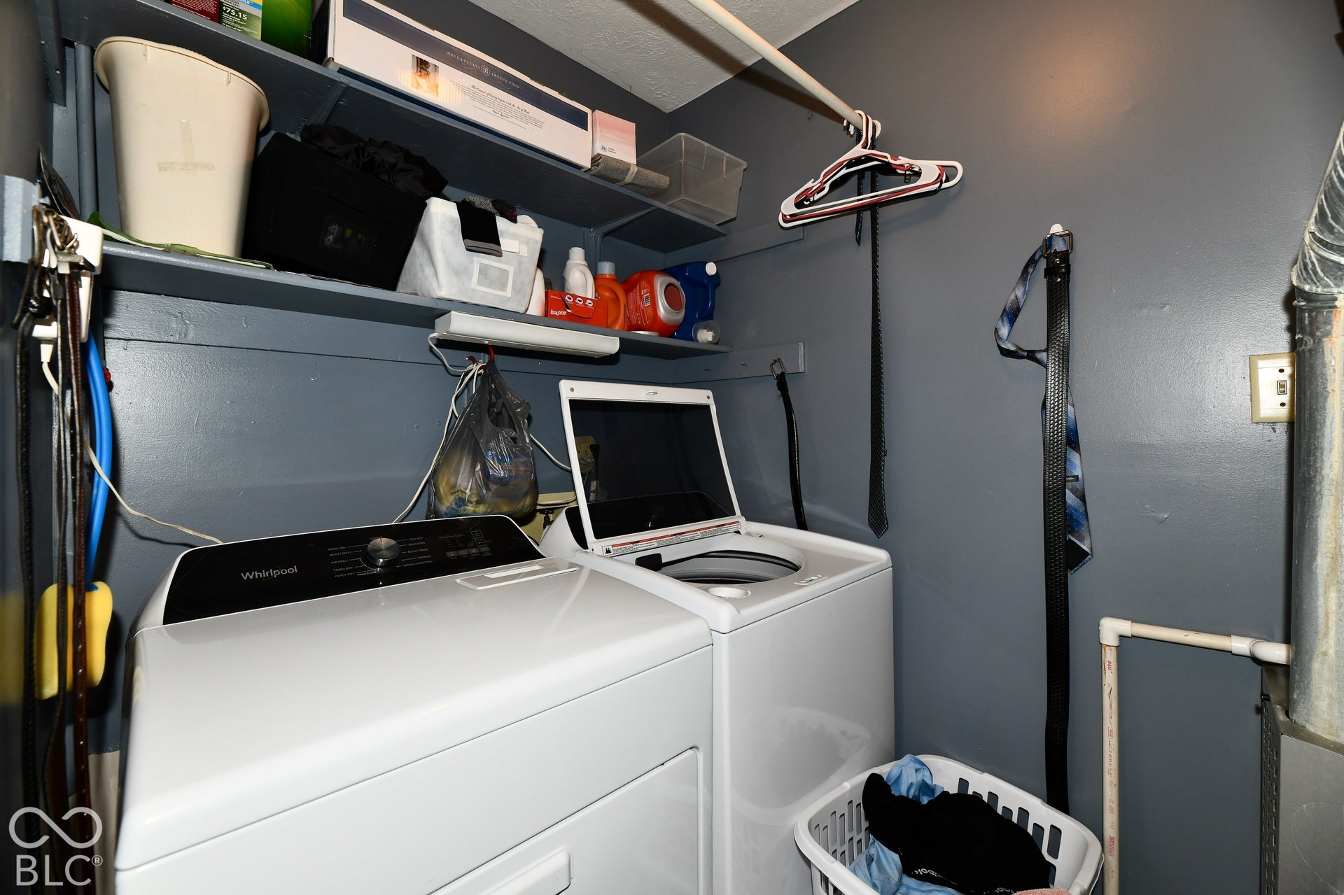Laundry area featuring dual overhead shelving units and a mounted clothing rod