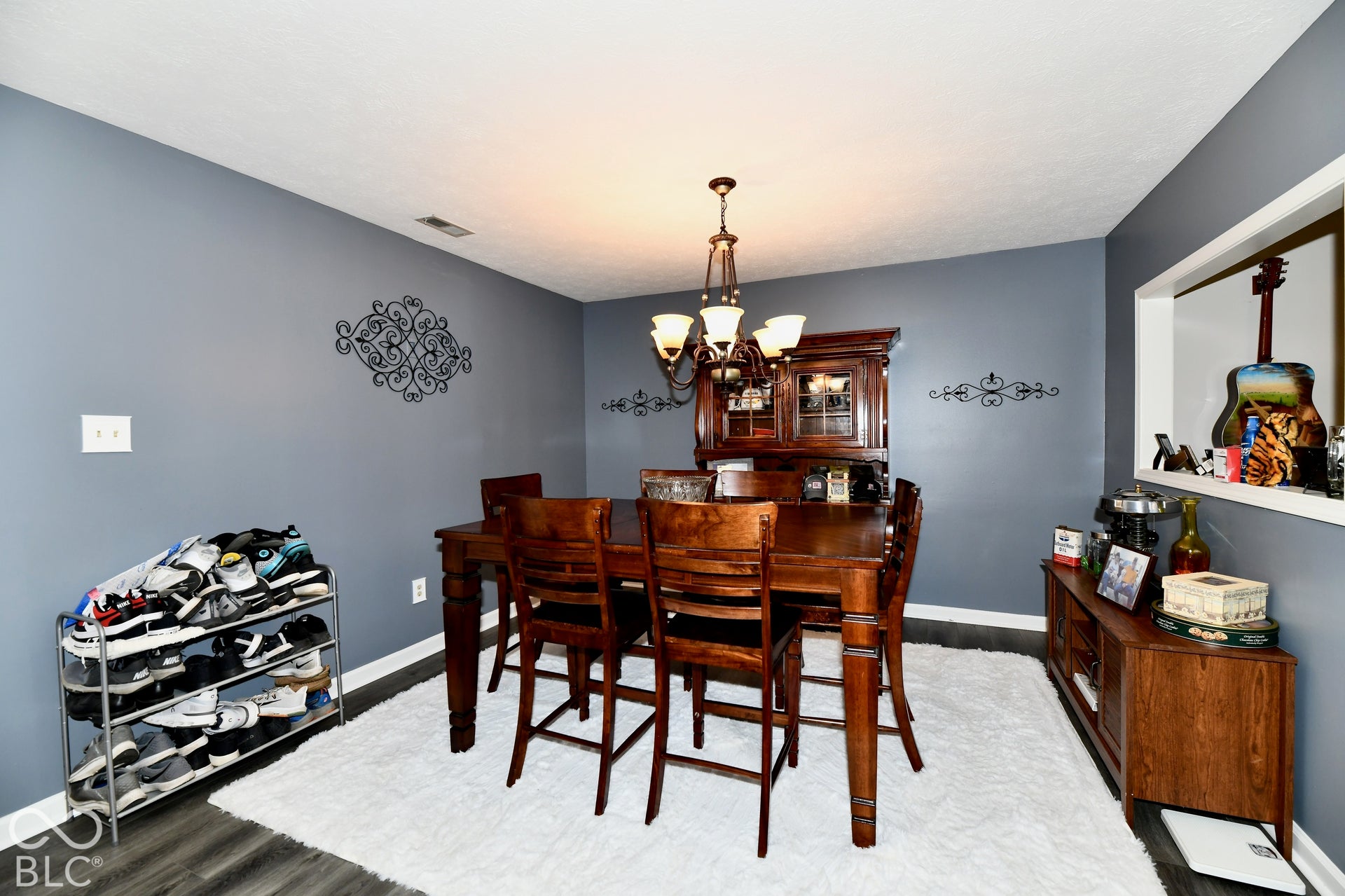 Dining area featuring wood-finish flooring, a multi-light chandelier, and a pass-through wall opening