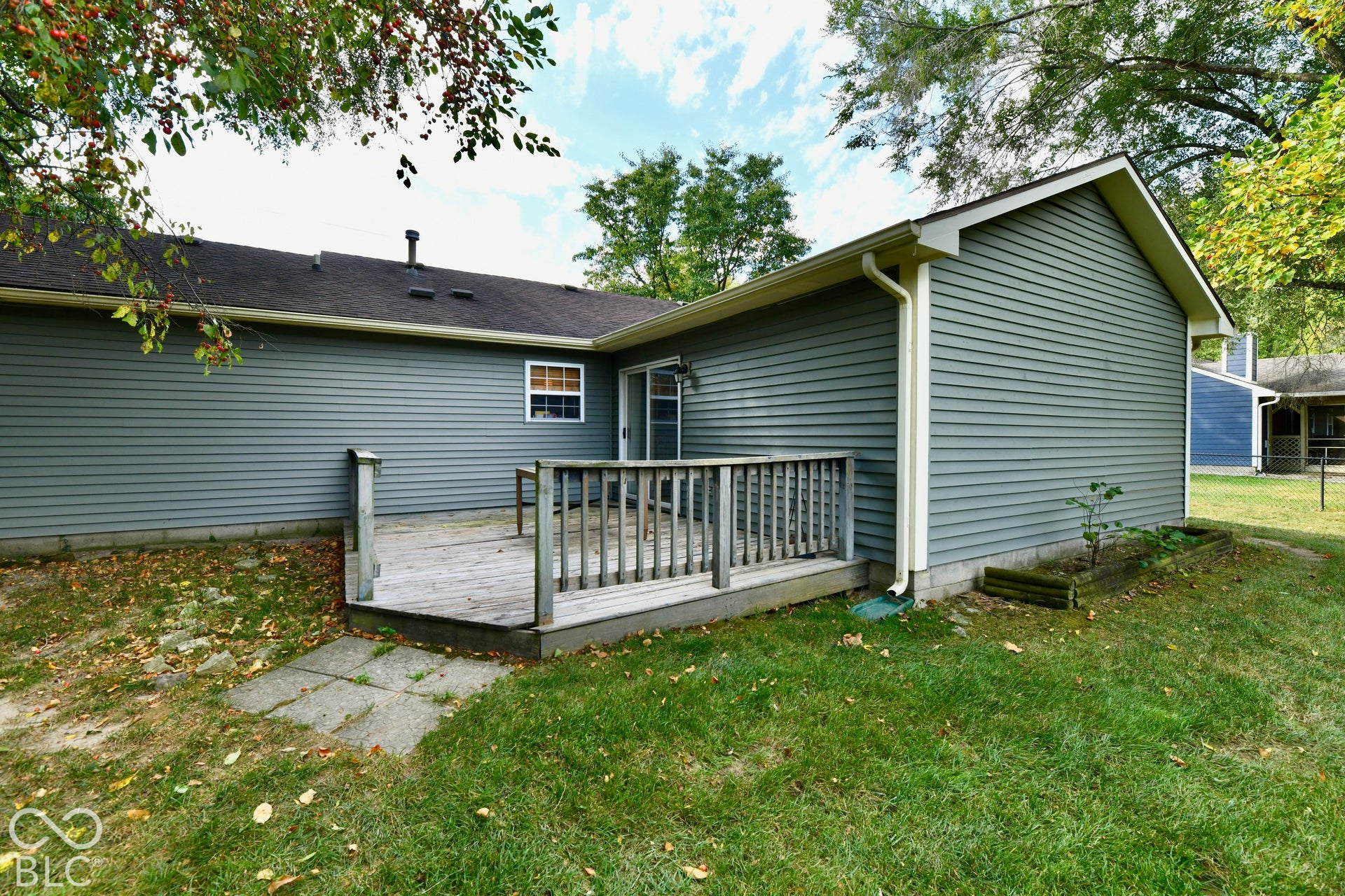 Exterior featuring horizontal siding, a raised wooden deck with railings, and a concrete paver walkway
